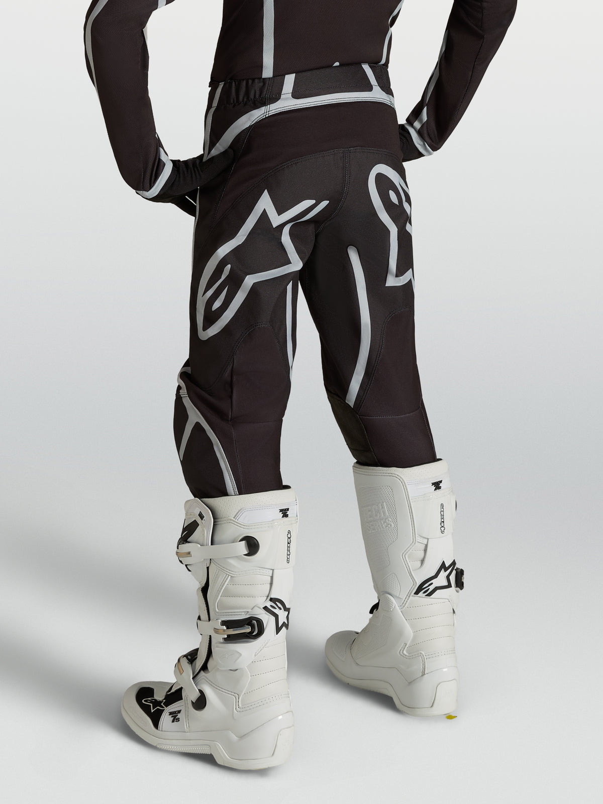 Alpinestars Youth Fluid Apex V2 Pants, Motocross Racing Gear, Youth, Black and Silver, Rear view with white boots.