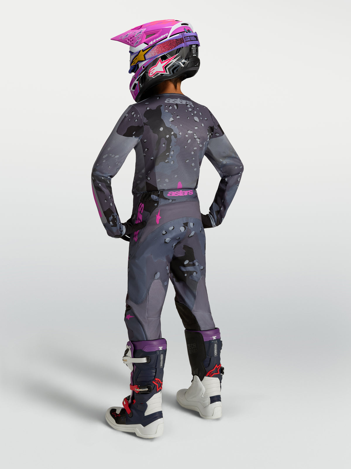Alpinestars 2027 Youth Fluid Lone Gear Set, gray and pink motocross gear, rear view on rider with helmet and boots.