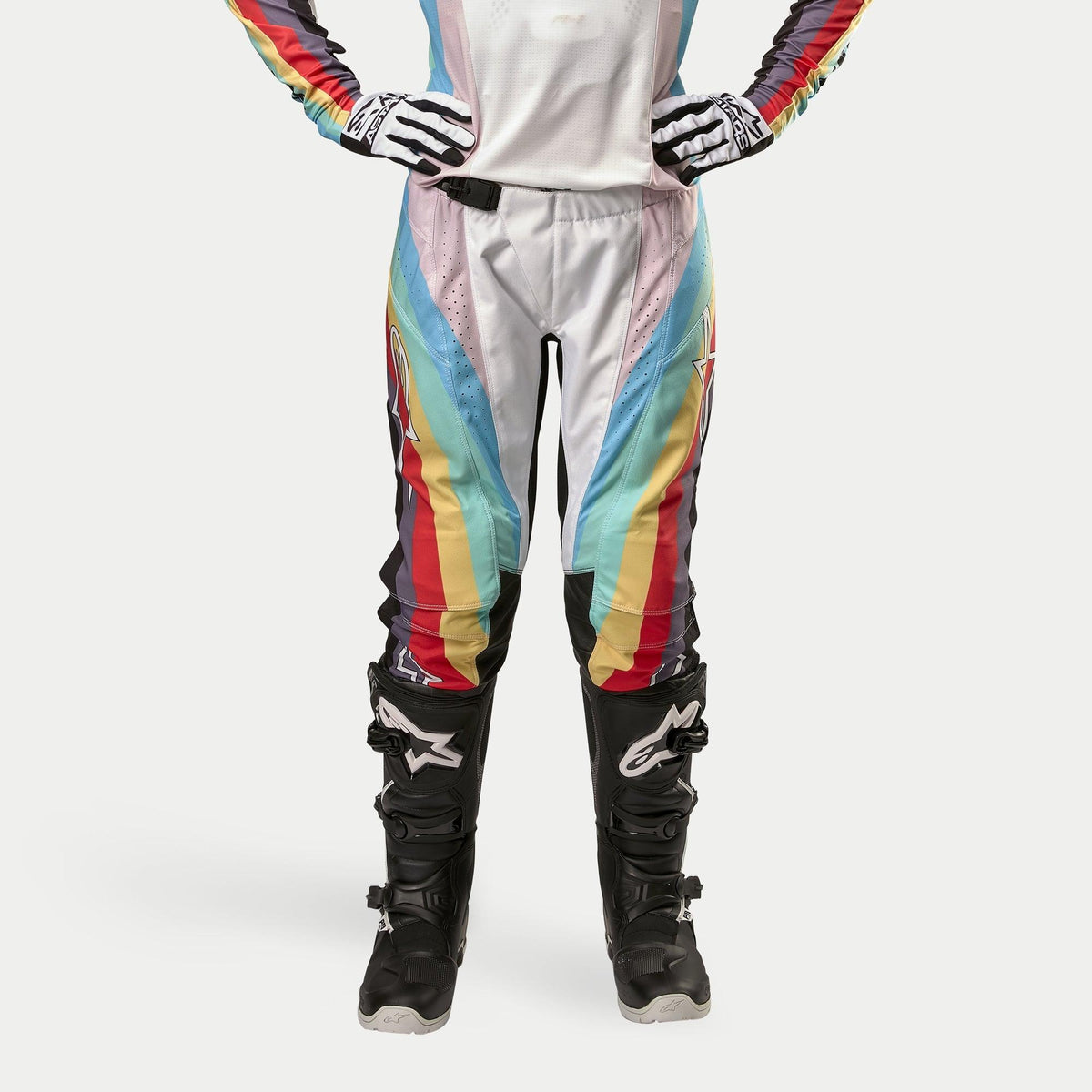 Alpinestars Women Stella 2024 Techstar Pants, Motocross Pants, Black Multicolor, featuring vibrant diagonal stripes in white, blue, red, and yellow, worn with black motocross boots and gloves, racing-inspired design for off-road performance.