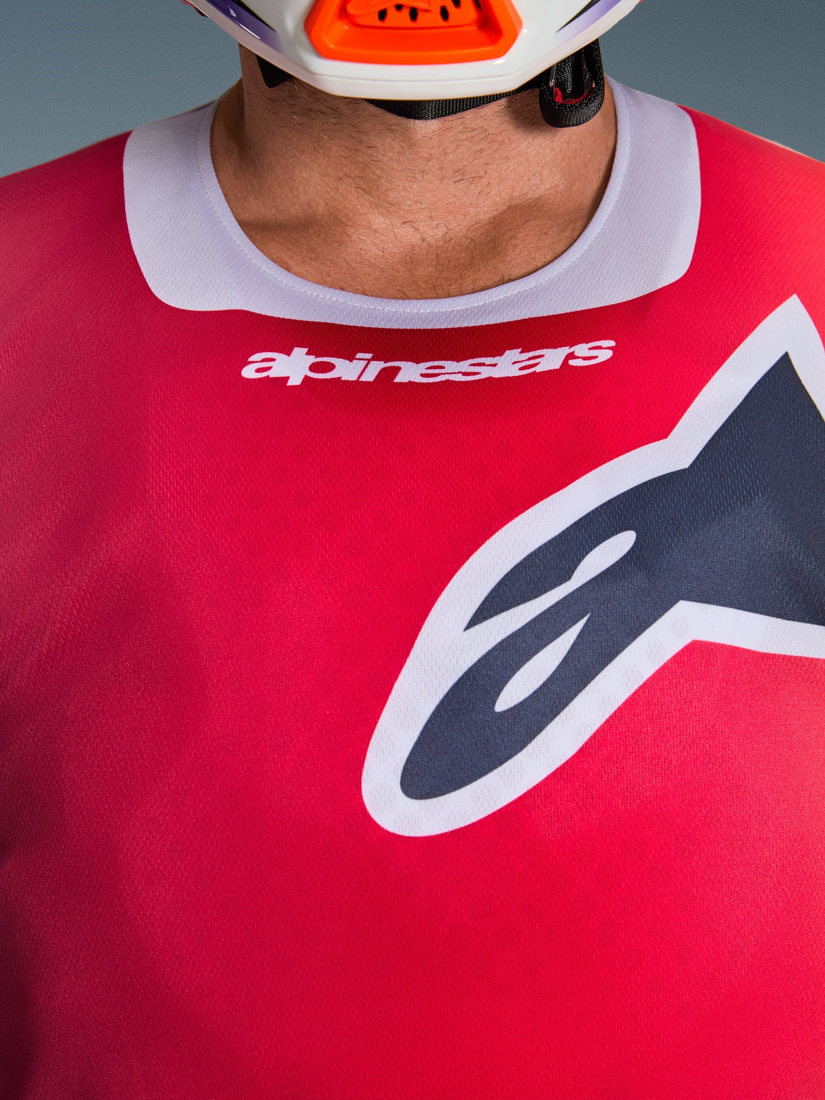 Alpinestars 2026 Racer Portl Jersey, close-up view of the chest and collar area, Red with Light Gray neck trim, white Alpinestars text and large Astars logo, featuring a moisture-wicking technical fabric texture