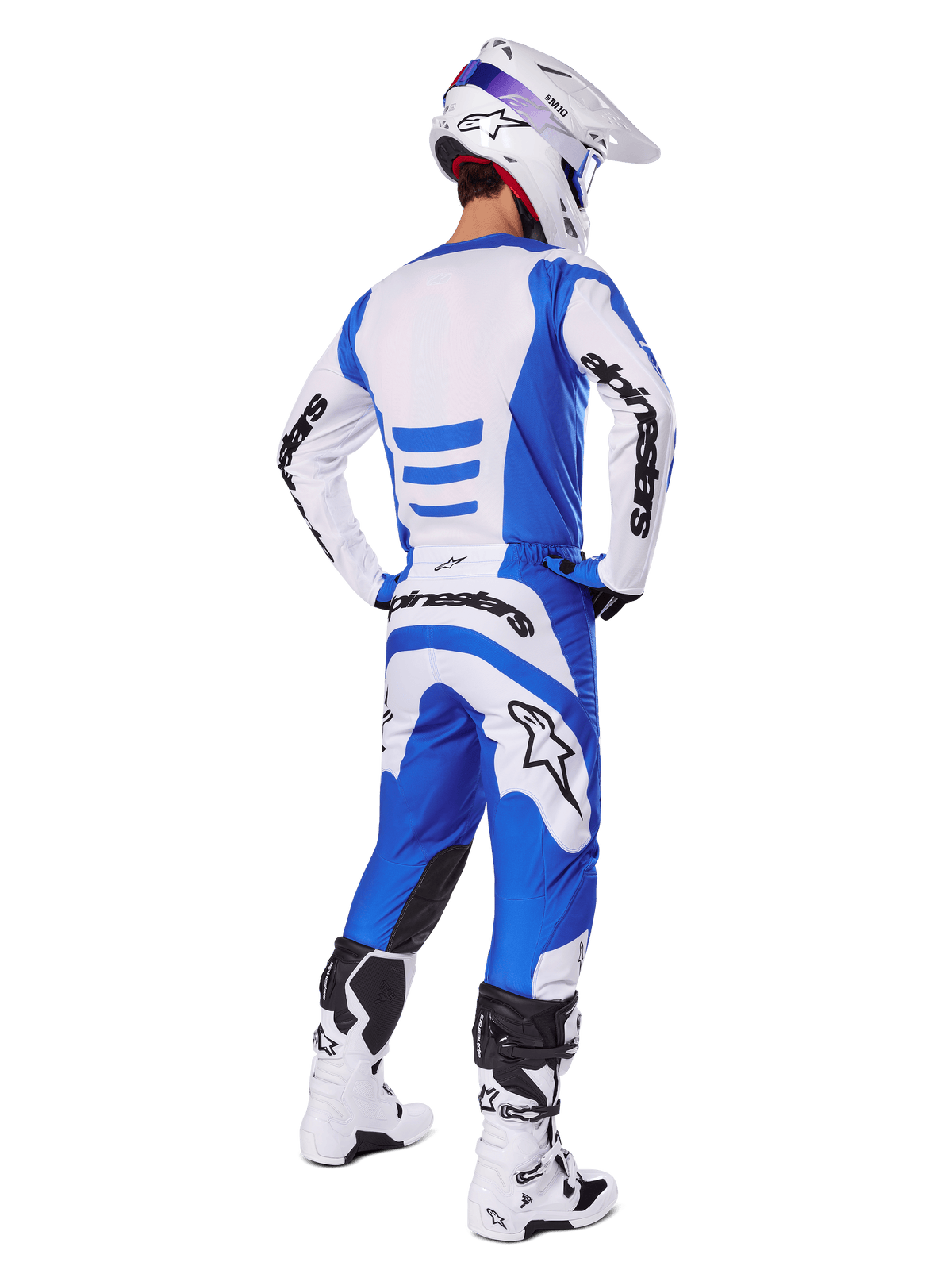 Motocross rider from the back wearing the Alpinestars 2025 Fluid Haul Gear Set, Blue and White jersey with matching pants, white helmet with blue accents, and white and black racing boots, coordinated off-road racing outfit