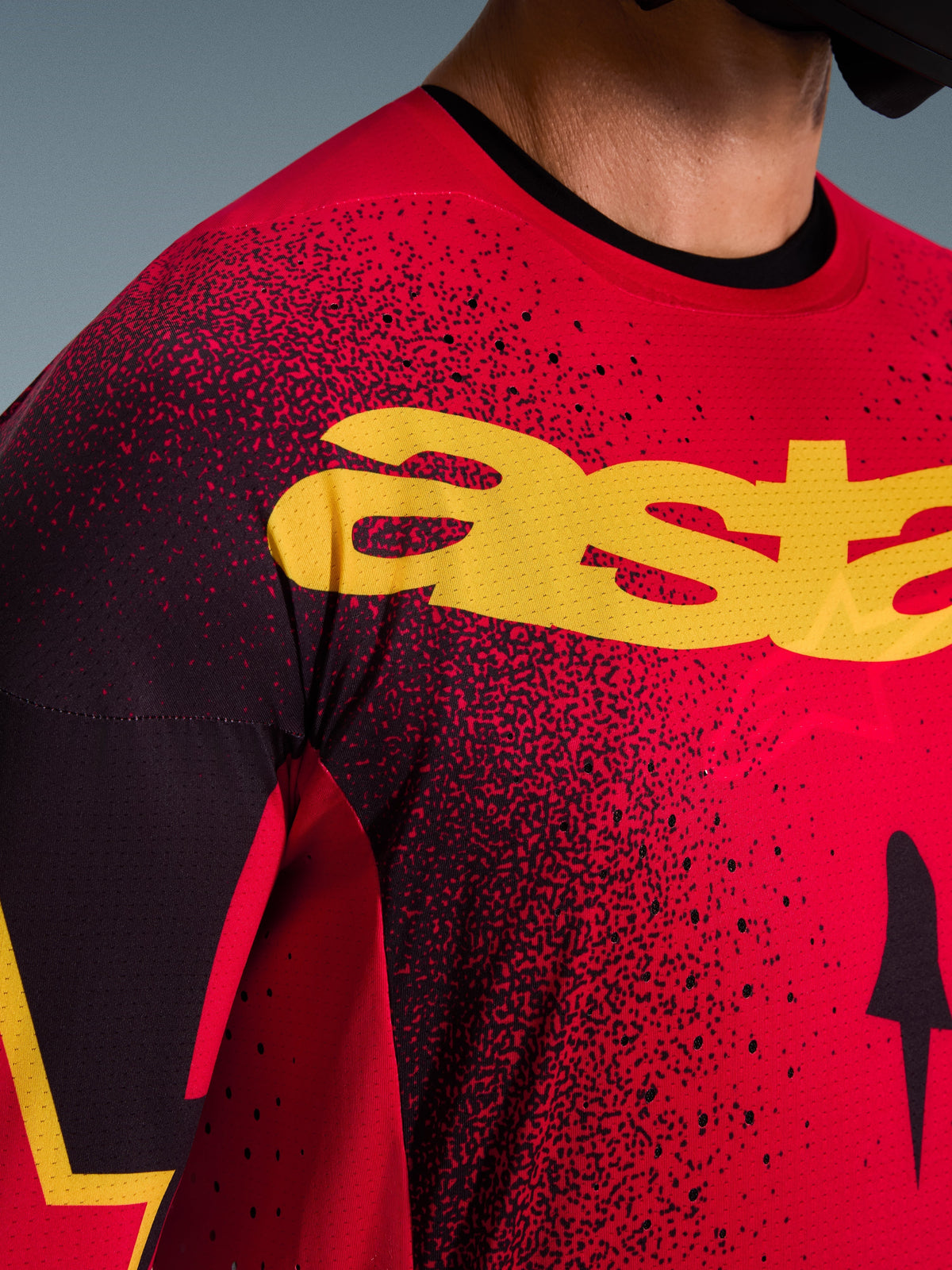 Close-up of the Alpinestars 2026 Supertech Scenz Jersey in Red Black Yellow, featuring a large yellow logo on the chest, laser-cut perforations for enhanced airflow, and a lightweight mesh texture for professional motocross racing.