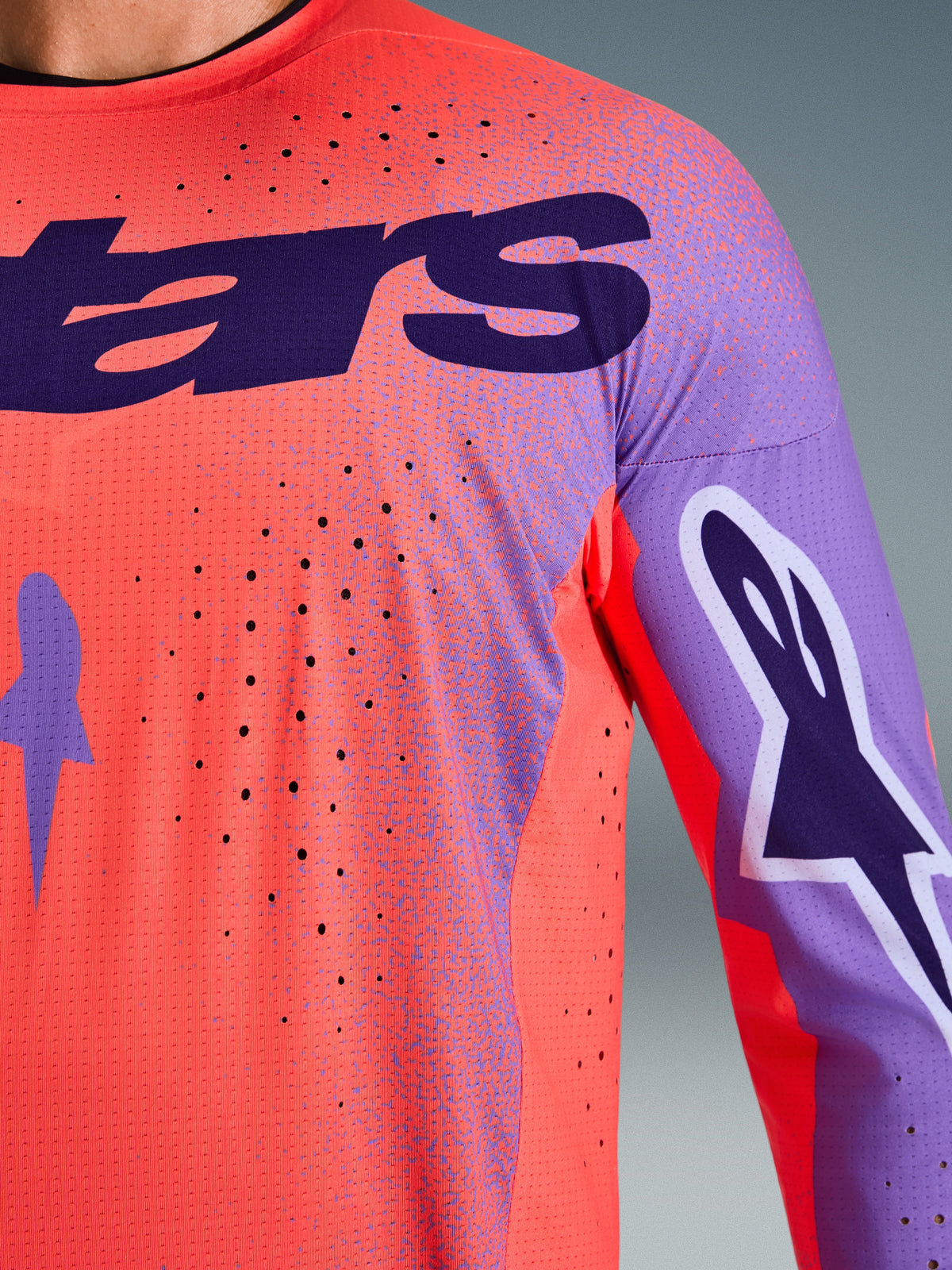 Alpinestars 2026 Supertech Scenz Jersey, Motocross Jersey, Hot Coral and Purple, close-up view showing breathable mesh texture and laser-cut perforations, featuring large purple chest logo and sleeve graphics for professional off-road racing.
