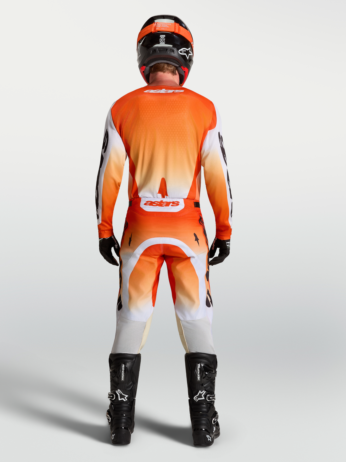 Alpinestars 2027 Racer Amber Gear Set, orange and red motocross jersey and pants, back view on rider with black boots.