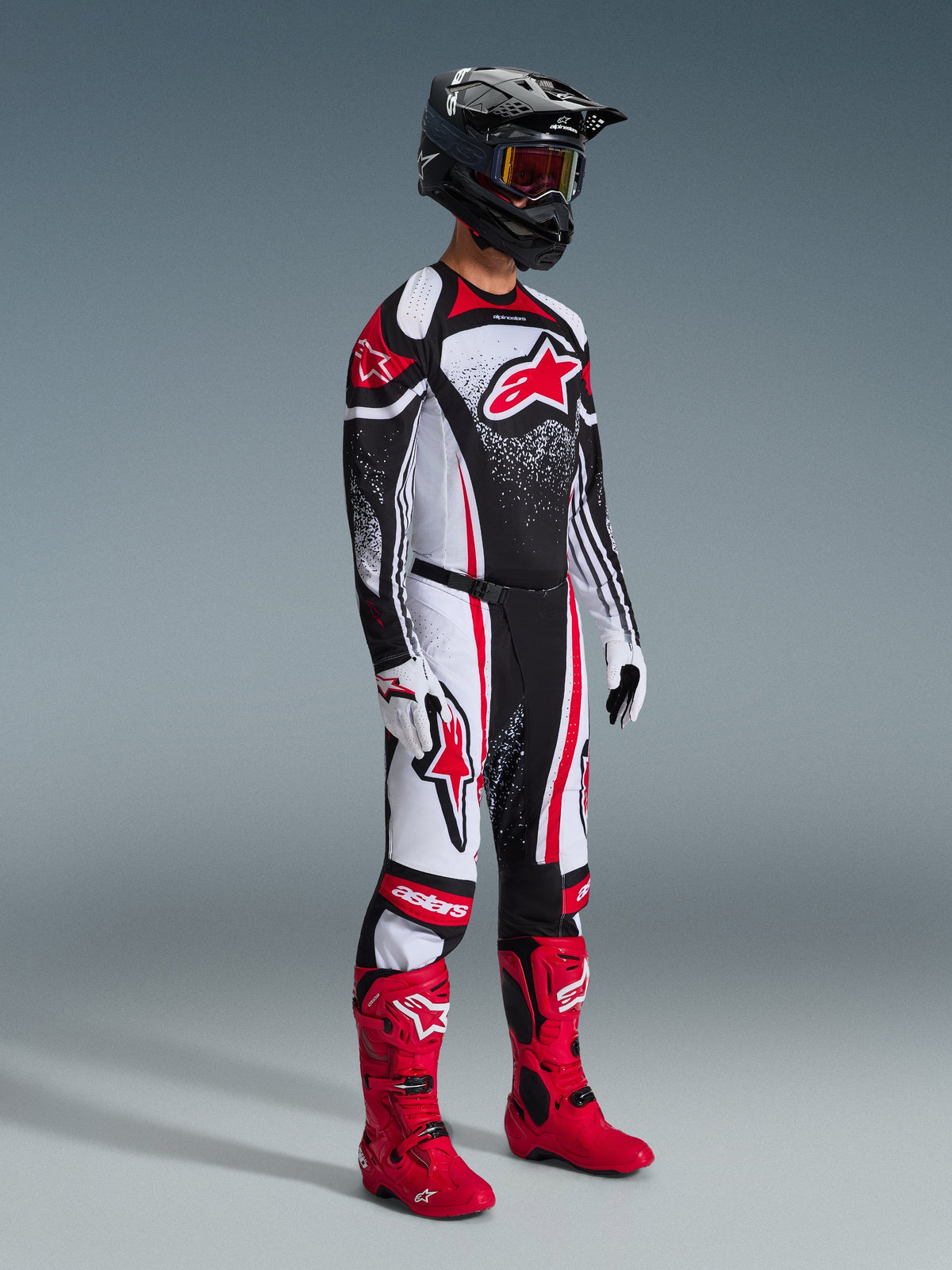 Motocross rider wearing 2026 Techstar Nomur Jersey, Black White and Red racing gear, matching pants with red accents, black helmet, bright red boots, white and black gloves, full professional motocross outfit for off-road competition.