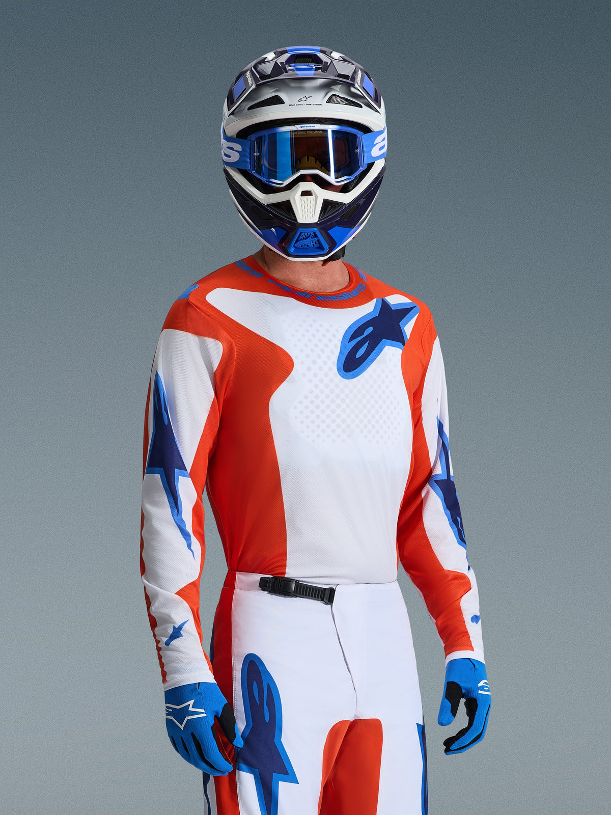 Alpinestars 2026 Fluid Grid Jersey, Motocross Jersey in Orange UCLA Blue, worn by a rider with matching white and orange pants, blue and white helmet, blue goggles, and blue gloves, complete off-road racing gear set