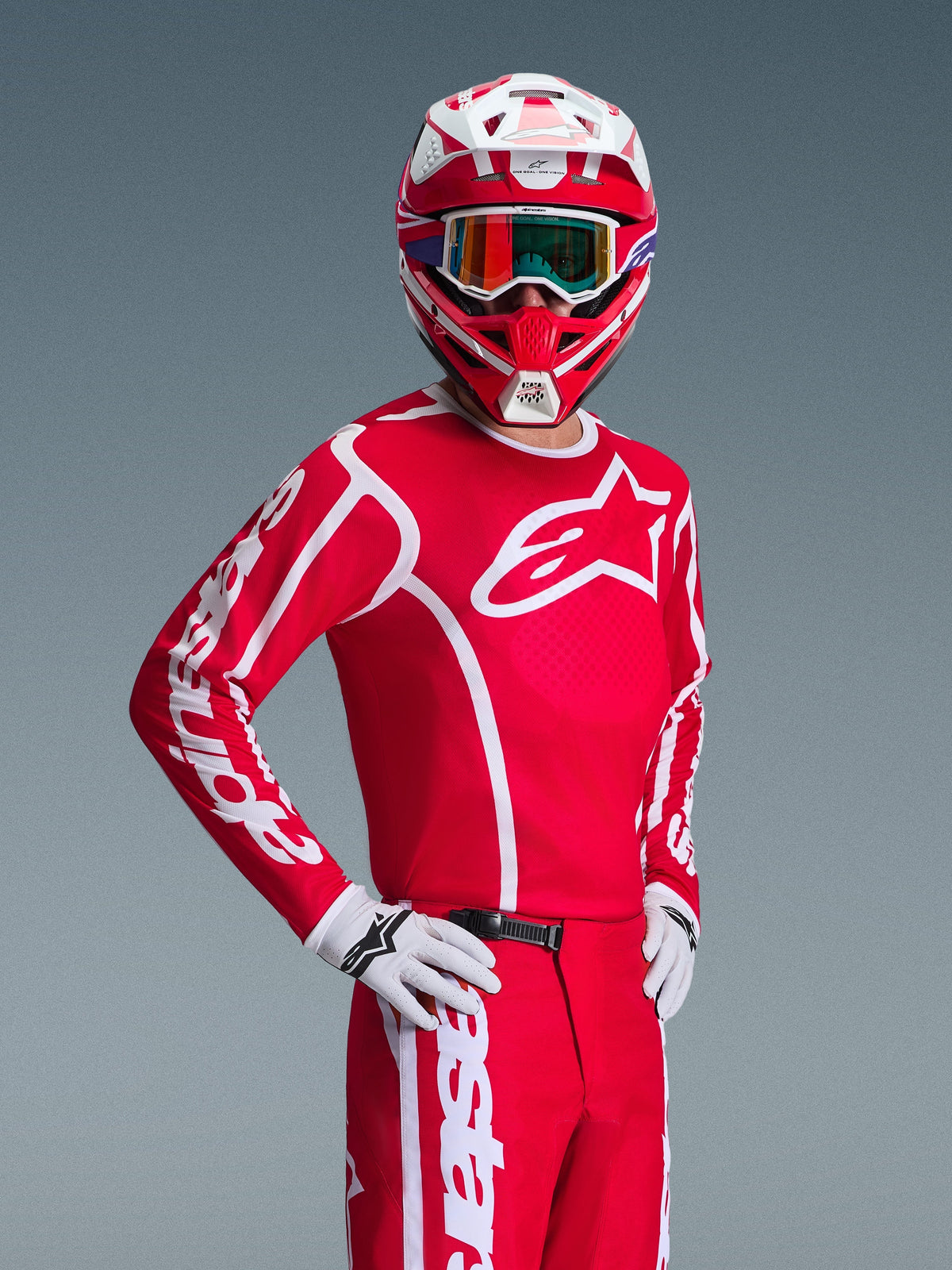 Motocross rider wearing Alpinestars 2026 Fluid Apex Jersey in Red and White, matching red and white helmet with goggles, white gloves, and red pants, featuring bold white logos and athletic fit, coordinated outfit for off-road racing