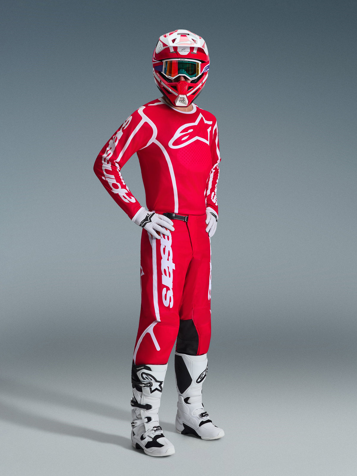 Motocross rider wearing the Alpinestars 2026 Fluid Apex Gear Set, Red jersey with large white logos, matching red pants with white branding, white and red helmet, white motocross boots and gloves, coordinated outfit for off-road racing