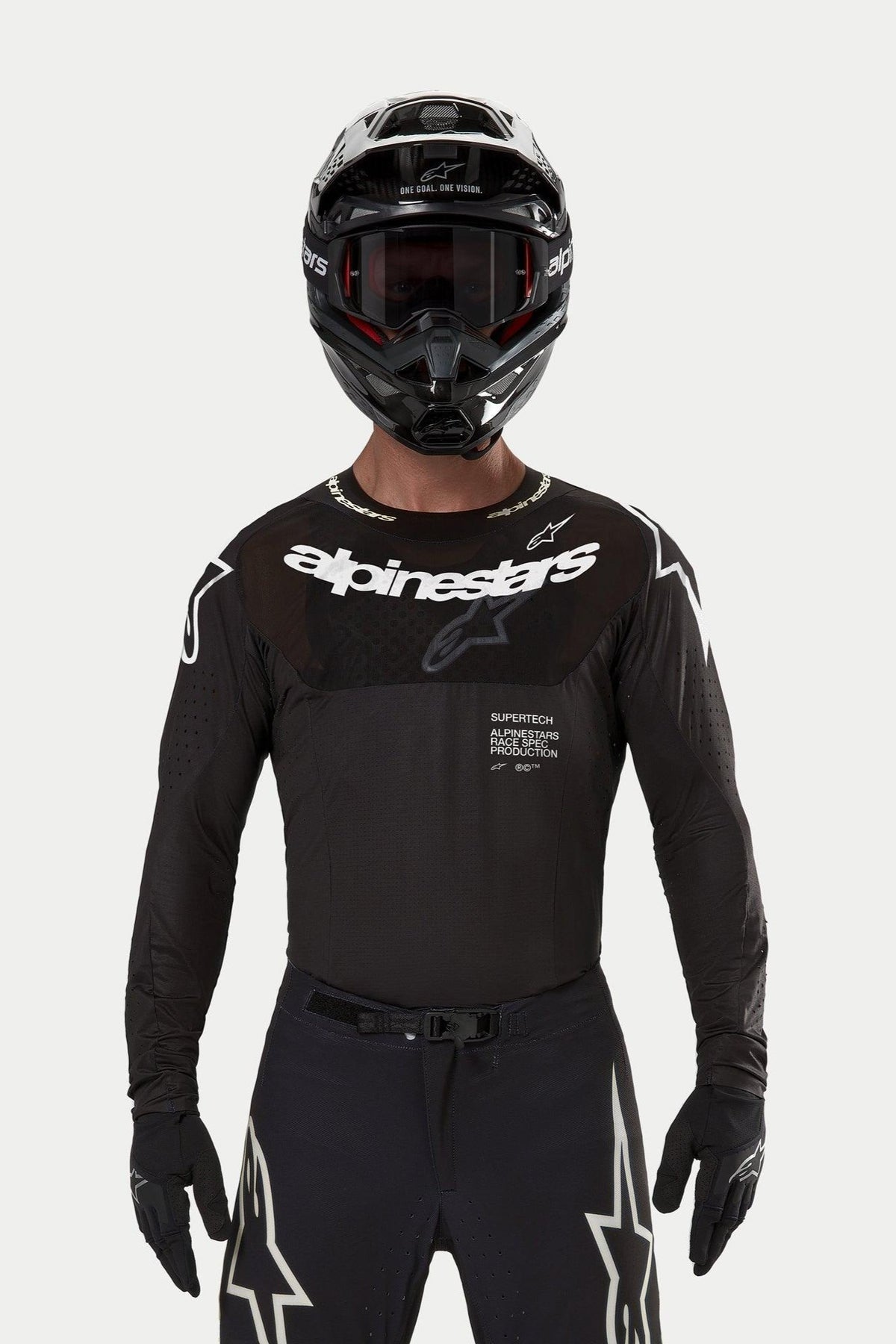 Motocross rider wearing the Alpinestars 2024 Supertech Ward Jersey in Black, athletic race fit with white Alpinestars logo on the chest, featuring laser-cut perforations and 'Supertech Race Spec' text, paired with a black helmet and goggles for off-road racing.