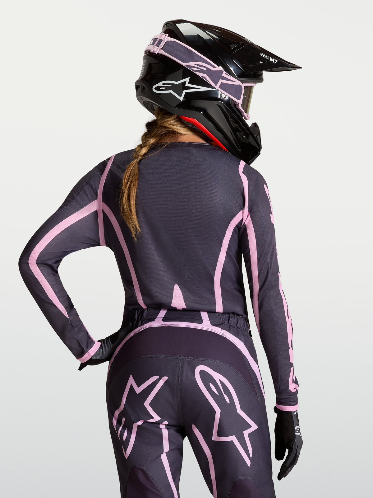 Alpinestars Stella Fluid Apex V2 Jersey, women's motocross gear in Graystone and Old Pink, moisture-wicking polyfabric riding shirt with extended rear coverage, shown on-model with a matching helmet.