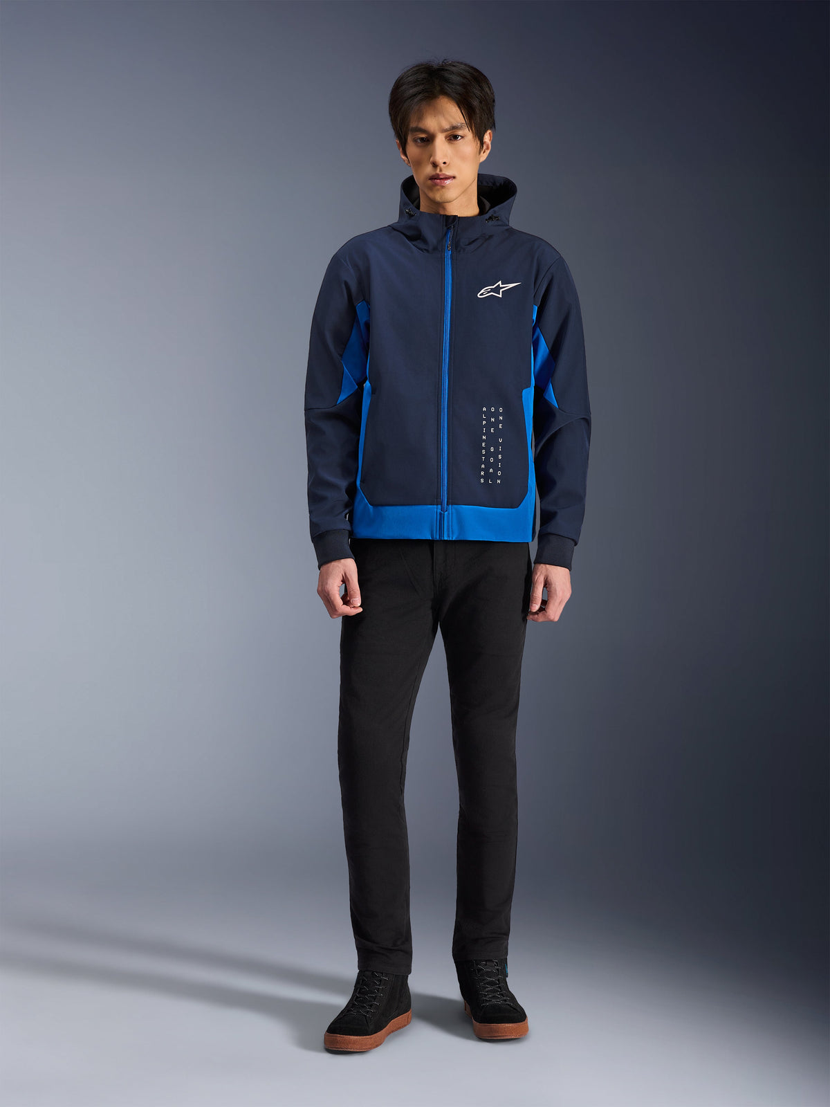 Alpinestars Radium Tech Hoodie, Night Navy and Royal Blue urban motorcycle hoodie, windproof technical shell, casual streetwear design worn with black pants and high-top sneakers, features white logo branding on the chest.