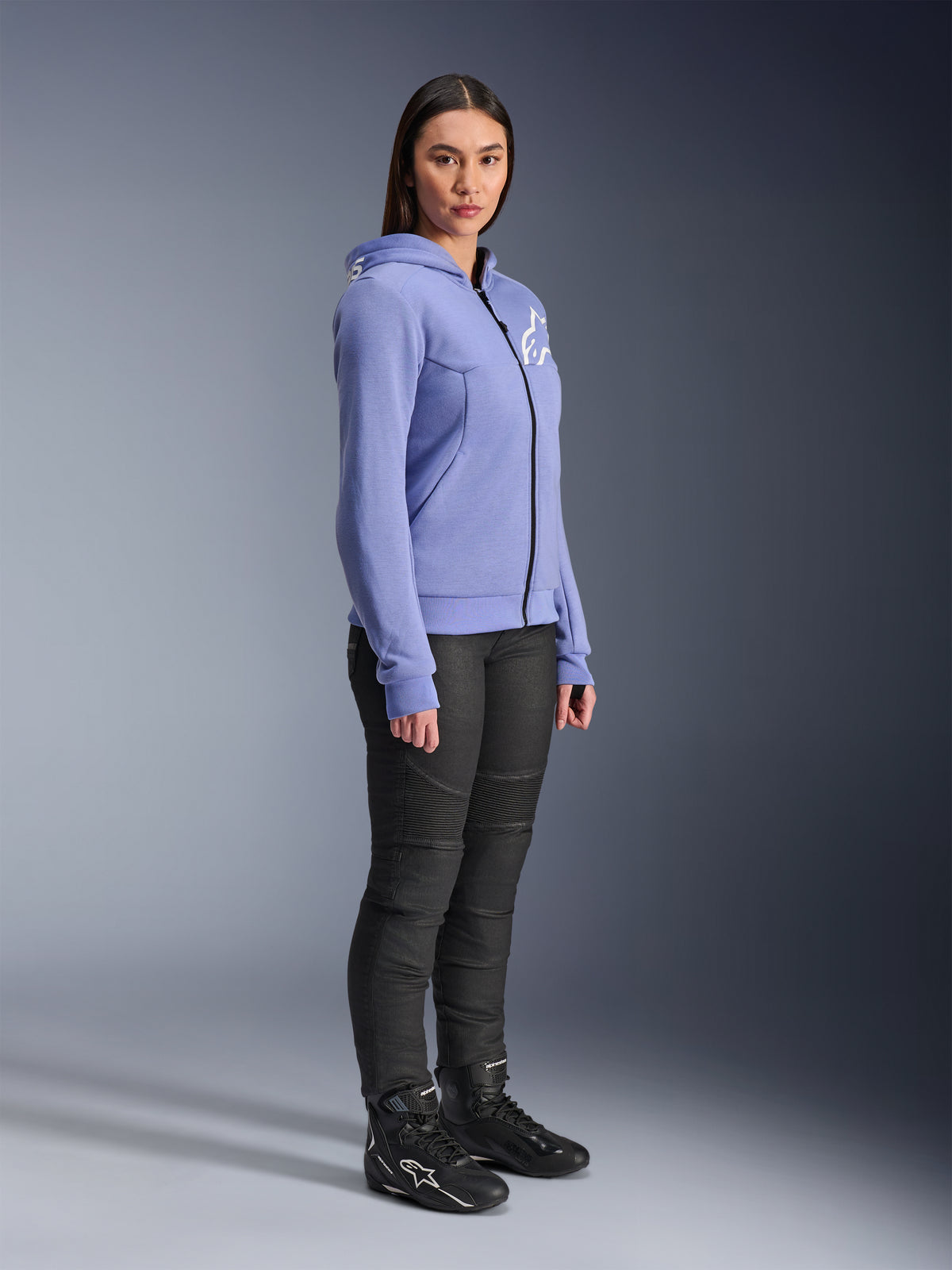 Alpinestars Woman Stella Chrome V2 Sport Hoodie, motorcycle hoodie in blue-violet with white Alpinestars logo on the chest, worn by a model with black riding pants and black motorcycle boots, urban riding apparel for women