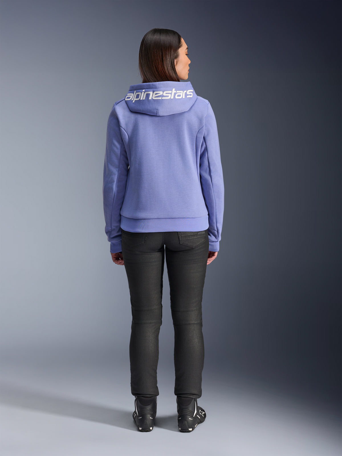 Alpinestars Stella Chrome V2 Sport Hoodie, Blue Violet, back view of a woman wearing the hoodie featuring white Alpinestars logo across the hood, paired with black pants and riding boots, casual urban motorcycle apparel