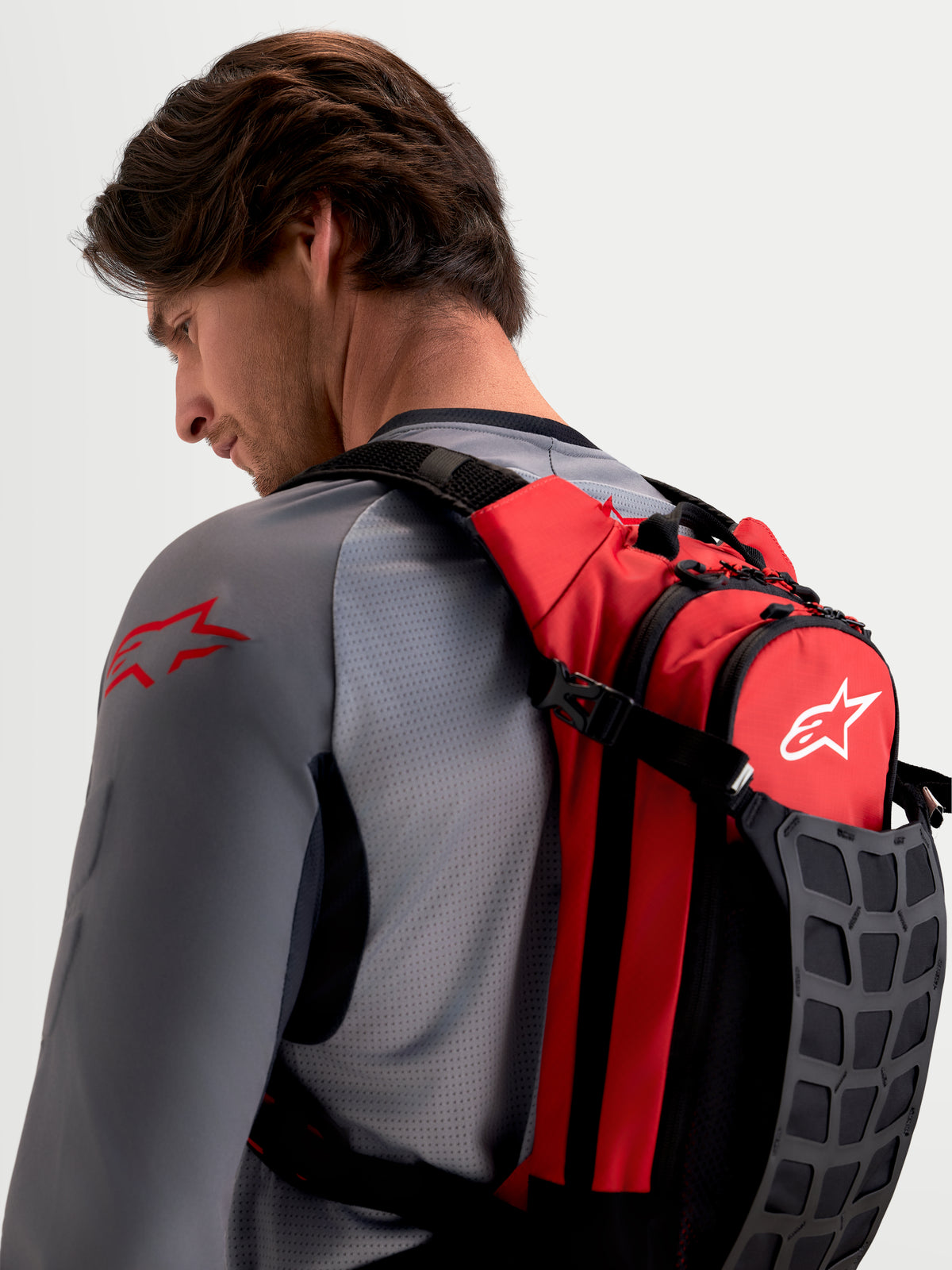Alpinestars AT-9 Back Pack, motocross backpack worn by a male model, red and black textile construction, featuring padded shoulder straps and organized storage for track essentials