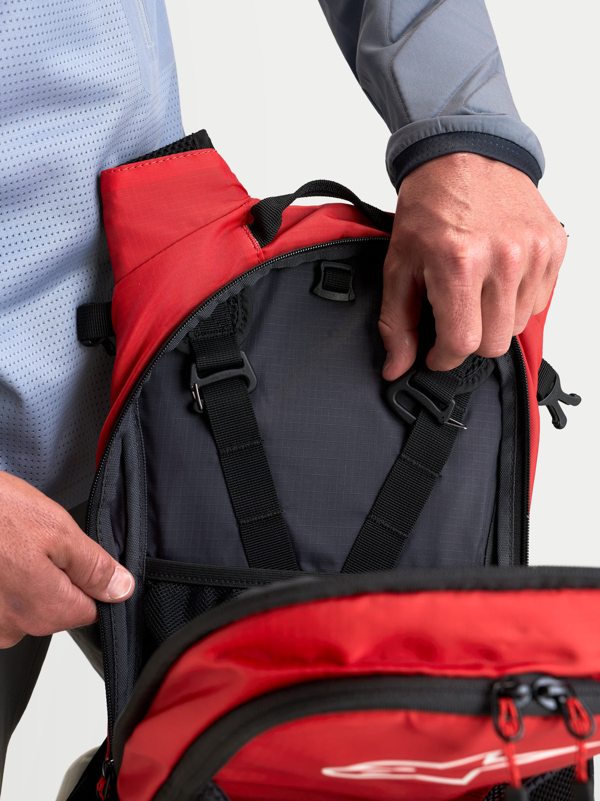 Alpinestars AT-9 Backpack, motocross and everyday utility backpack, black and bright red, close-up view of interior storage compartments and harness adjustment straps