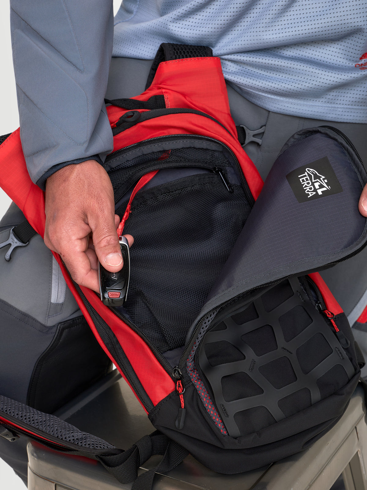 Alpinestars AT-9 Back Pack, motocross backpack in red and black, close-up view showing organized storage compartments and zip closure worn by a model.