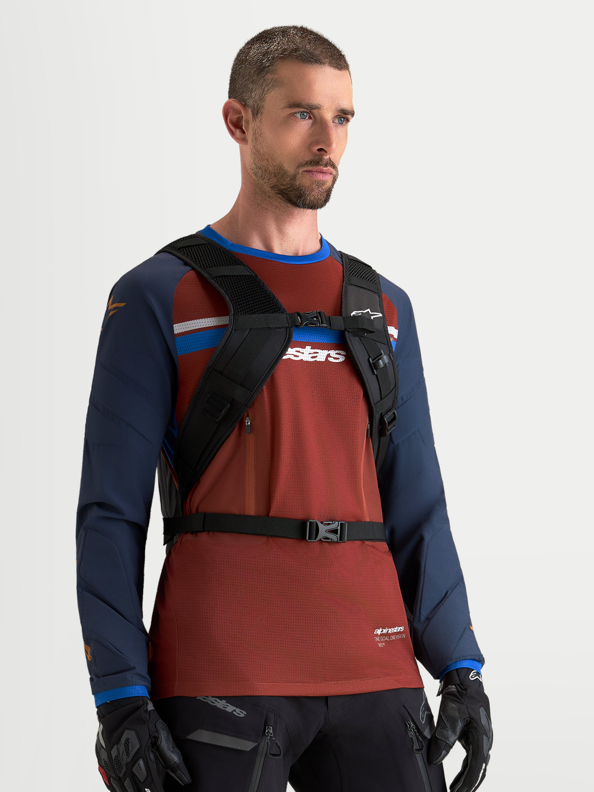 Alpinestars AT-9 Backpack, motocross backpack in black, worn by a male model showing the padded shoulder harness and chest strap system