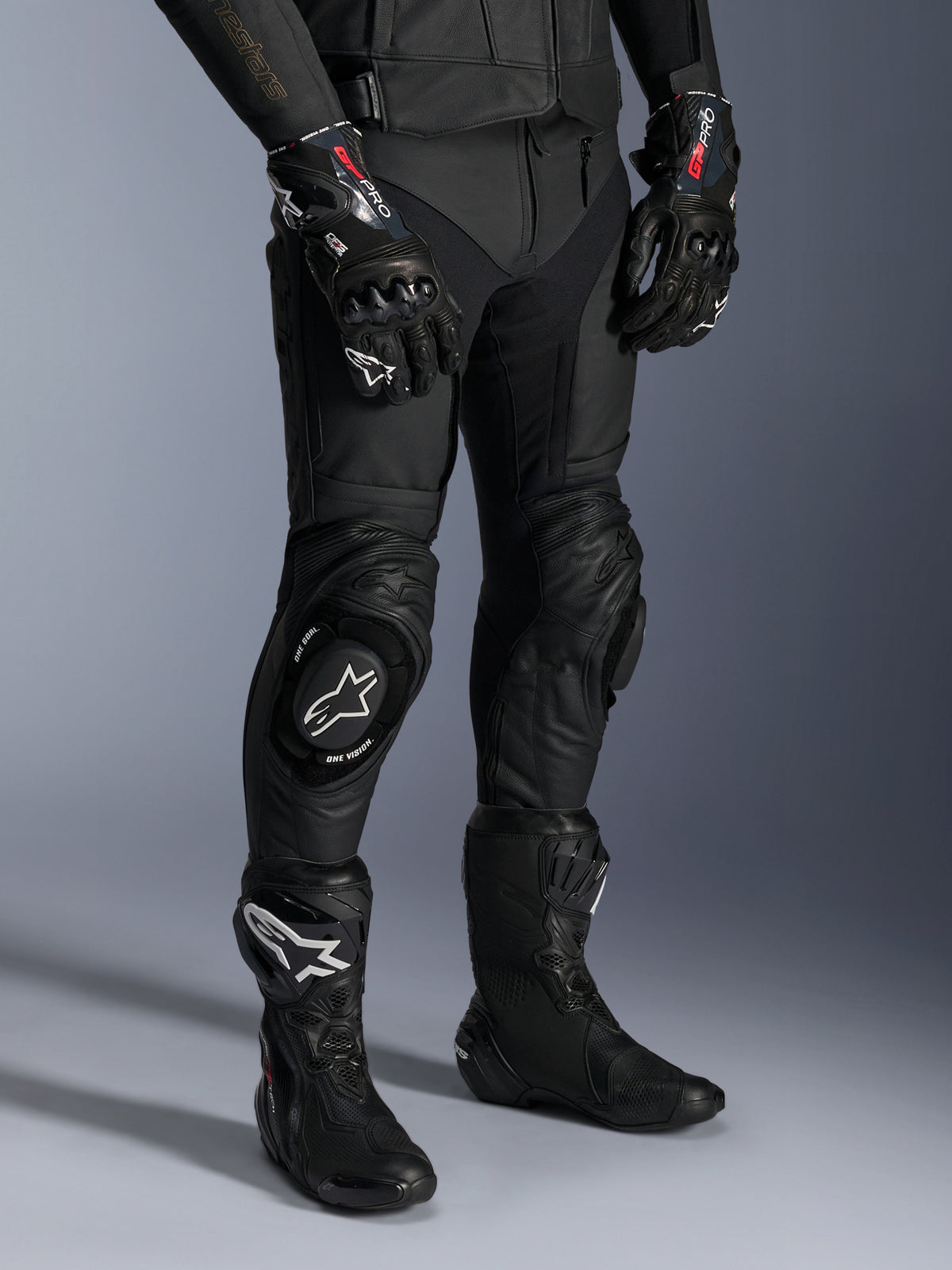 Missile V3 Leather Pants, Black Motorcycle Racing Pants, worn with matching GP Pro gloves and technical racing boots, premium leather construction with white logo knee sliders, professional racing aesthetic for track and road use