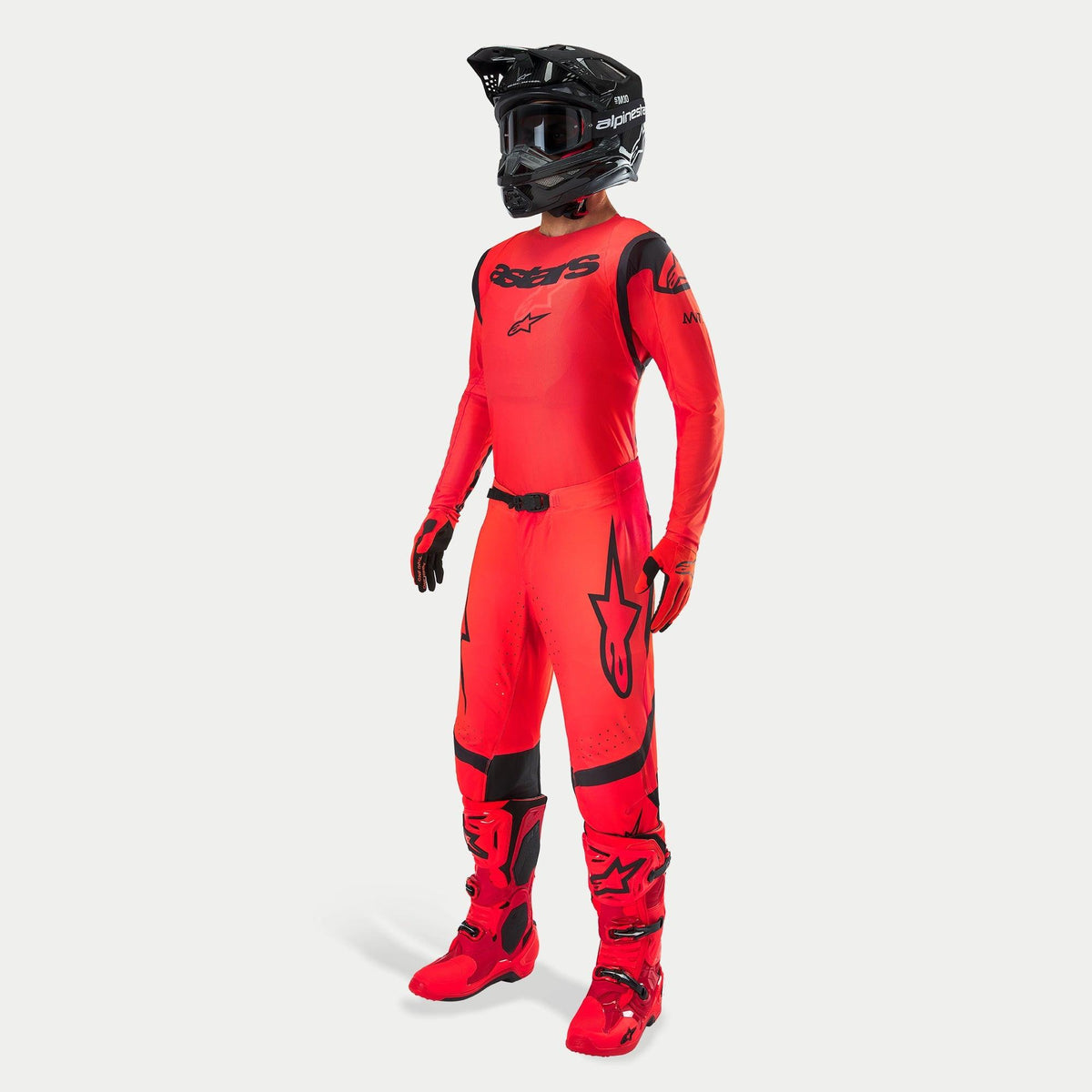 Motocross rider wearing complete racing gear, Supertech Ember LE Jersey and Pants in Red Fluo and Black, black helmet with goggles, matching red and black boots and gloves, coordinated professional outfit for off-road racing