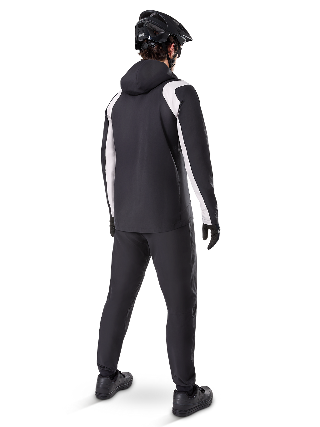Alpinestars A-Dura Rain Jacket, back view of a male cyclist wearing the black and white waterproof MTB jacket, matching black cycling pants, black helmet, and gloves, technical gear for mountain biking in wet conditions.