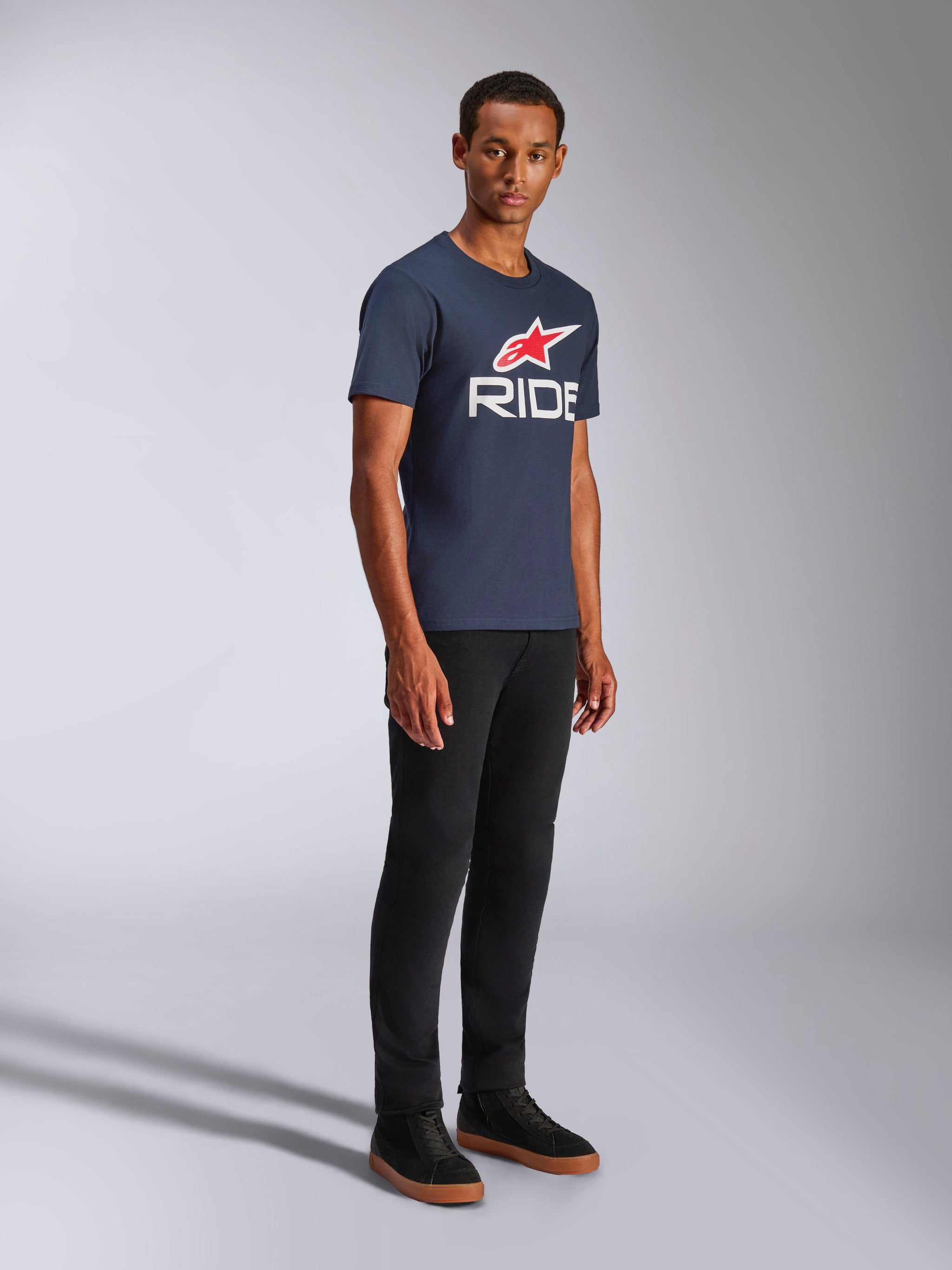 Alpinestars Ride 4.0 CSF Tee, Short Sleeve T-Shirt, Navy Blue, White RIDE logo with Red Alpinestars Star, worn by a model with black pants and sneakers, casual motorsport lifestyle apparel