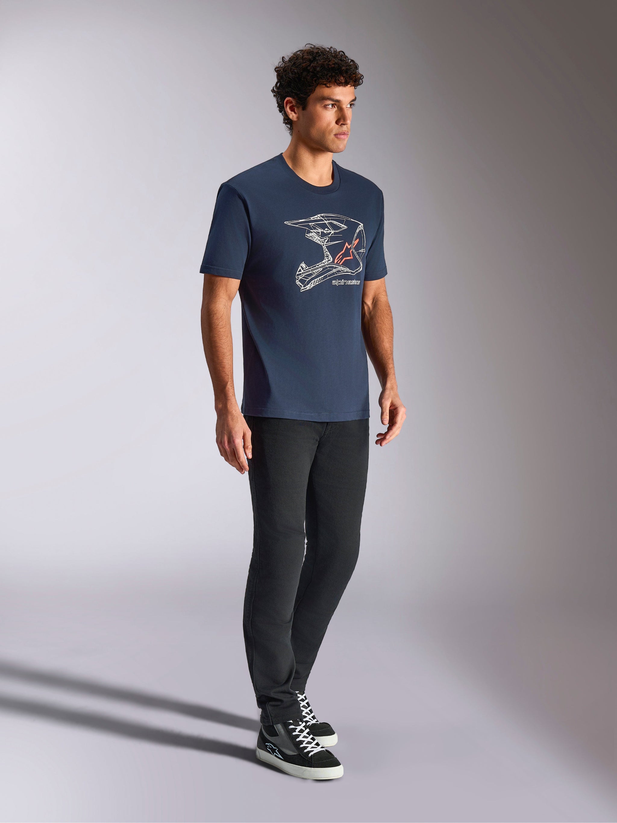 Alpinestars MX Helmet CSF Tee, Short Sleeve T-Shirt, Navy Blue, featuring white motocross helmet line art with red star logo, casual motorsport-inspired streetwear worn with black pants and high-top sneakers