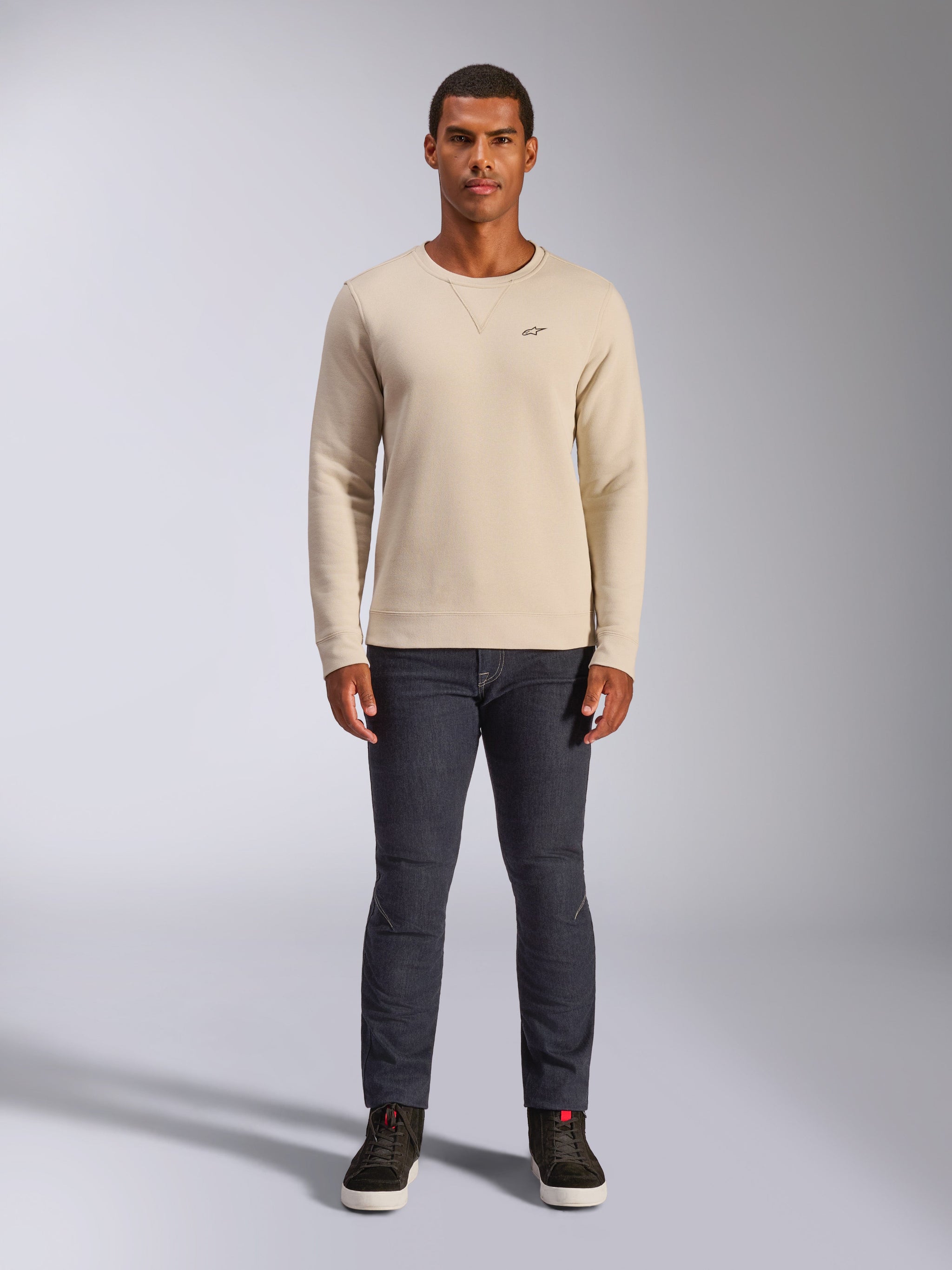 Alpinestars Positive Crew, Off White crewneck sweatshirt, small black logo on the chest, ribbed cuffs and hem, triangle neck stitching, casual motorsport streetwear worn with dark jeans