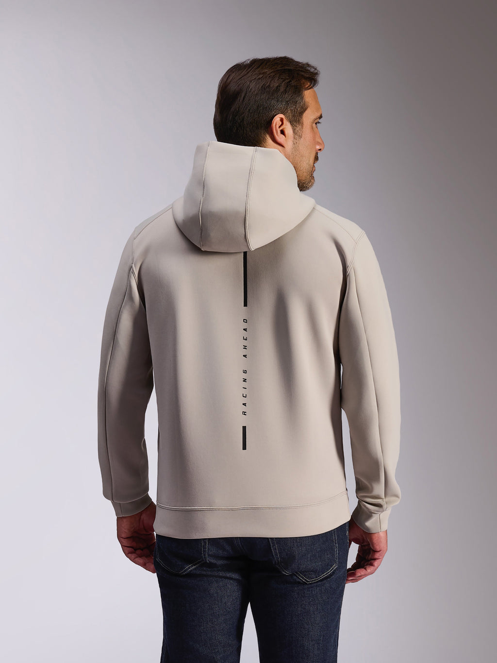 Alpinestars Insight Hoodie in Cement, back view of model wearing a light gray pullover sweatshirt, features a black vertical stripe logo with 'RACING AHEAD' text, casual motorsport-inspired double face fleece hoodie.