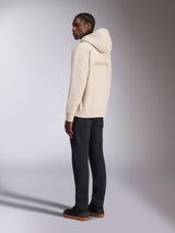 Alpinestars Emergent Oversized Hoodie in Sand, back view showing embroidered Alpinestars logo, oversized fleece pullover with hood, paired with black pants for a casual streetwear look