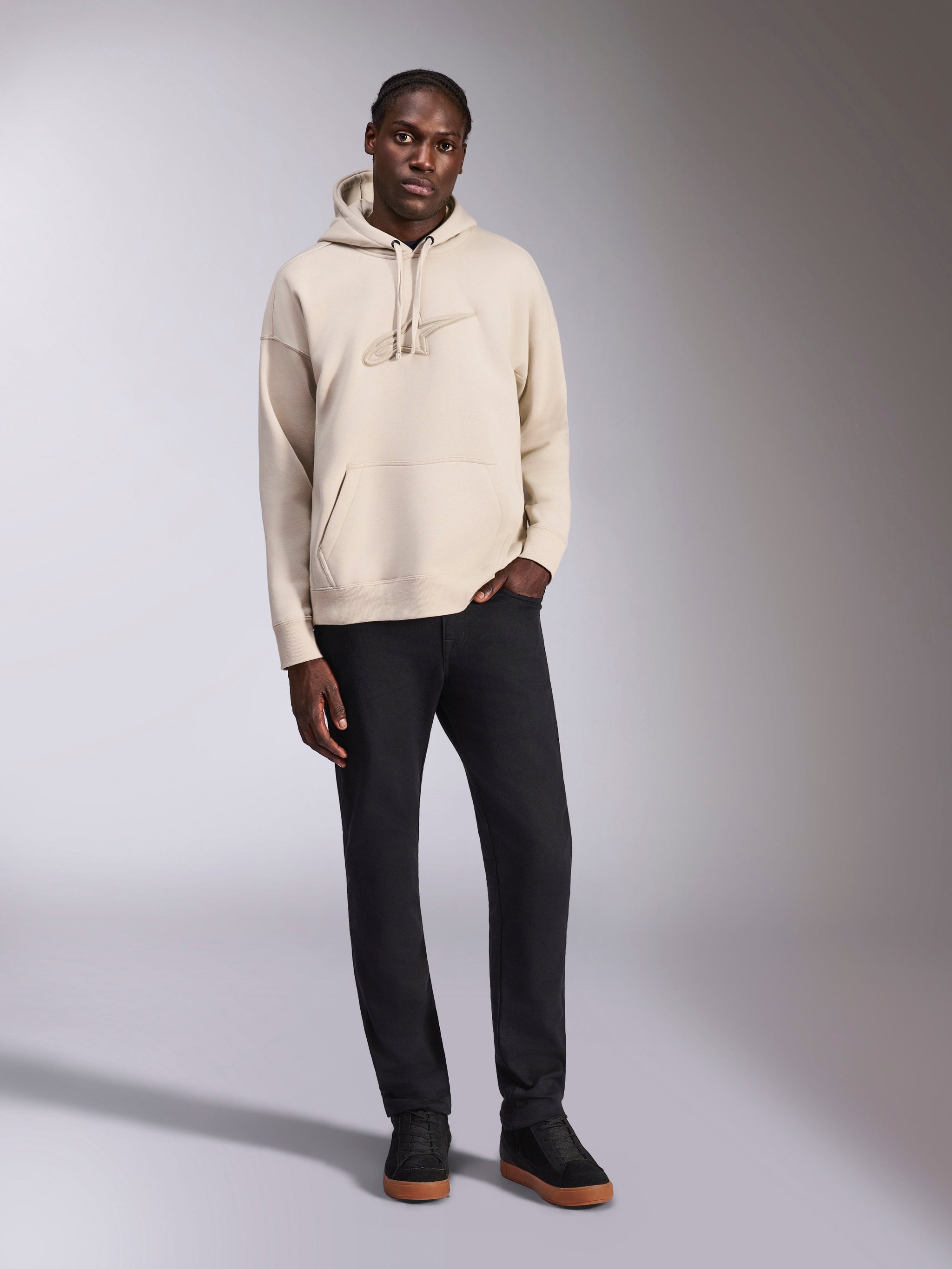 Alpinestars Emergent Oversized Hoodie, pullover fleece hoodie, Sand, tonal 3D embroidered Astars logo on chest, oversized fit with kangaroo pocket and drawstring hood, casual motorsport-inspired streetwear worn with black pants