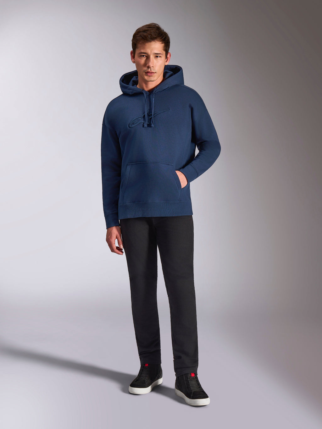 Alpinestars Emergent Oversized Hoodie, Navy Blue pullover fleece hoodie, tonal 3D logo embroidery on front, worn by model with black pants and sneakers, casual streetwear style.