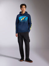 Alpinestars Obsessed Hoodie, Navy Blue pullover hoodie, front Astars logo with blue MX gradation and lime yellow star, lime yellow Alpinestars word sleeve logos, worn by a model with black cargo pants and black sneakers, casual motorsport-inspired streetwear