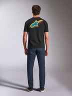 Alpinestars Angler CSF Tee, Short Sleeve T-Shirt, Black, Back view of model wearing shirt with large vibrant multi-color Astars star logo and 'RACING AHEAD' text, paired with dark blue jeans, casual motorsport streetwear