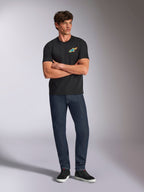 Alpinestars Angler CSF Tee, Short Sleeve T-Shirt, Black, Vibrant Multi-Color Astars Logo on Chest, worn by model with arms crossed, dark denim jeans and black sneakers, casual motorsport streetwear