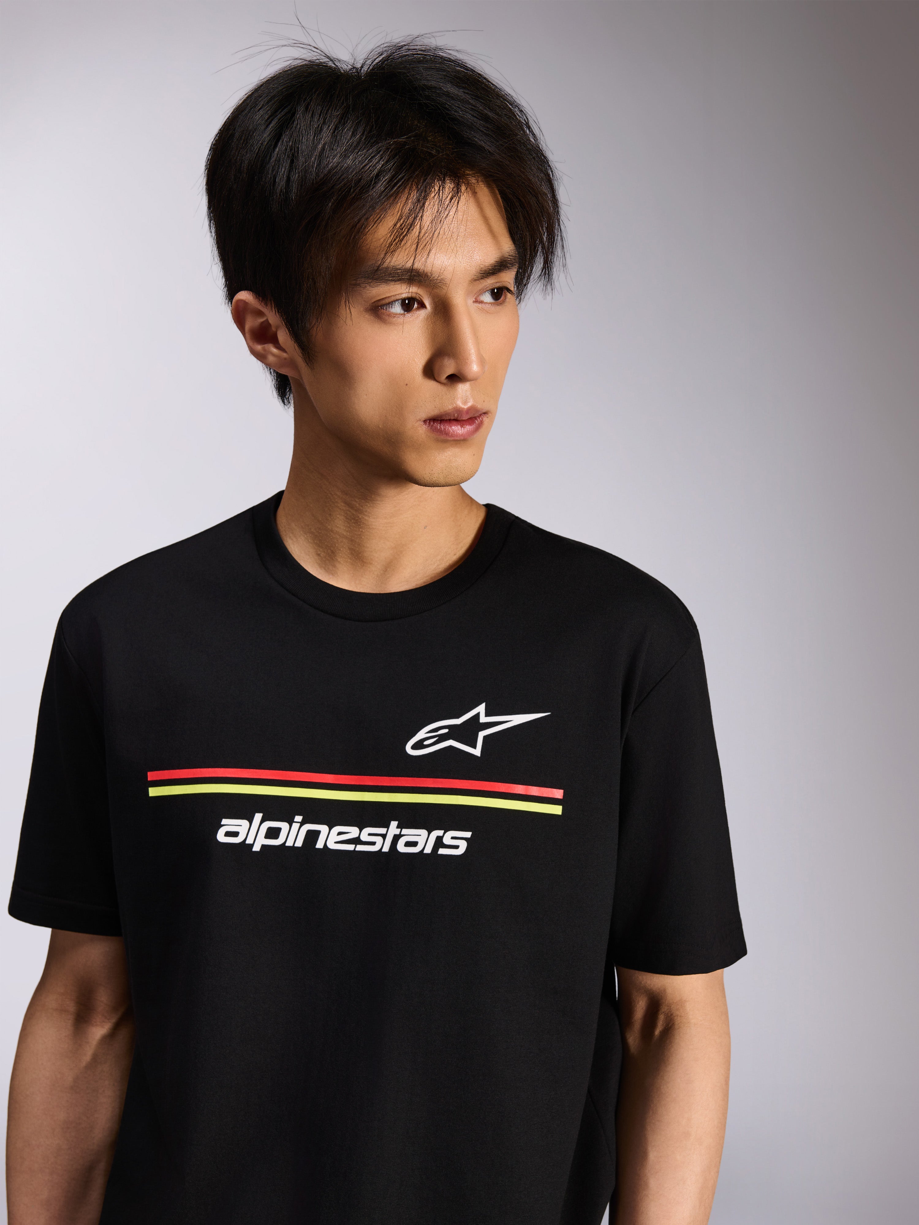 Alpinestars Lanes CSF Tee, Short Sleeve T-Shirt, Black, featuring white Astars and Alpinestars logos with red and yellow stripes, Casual Motorsport Streetwear worn by a model