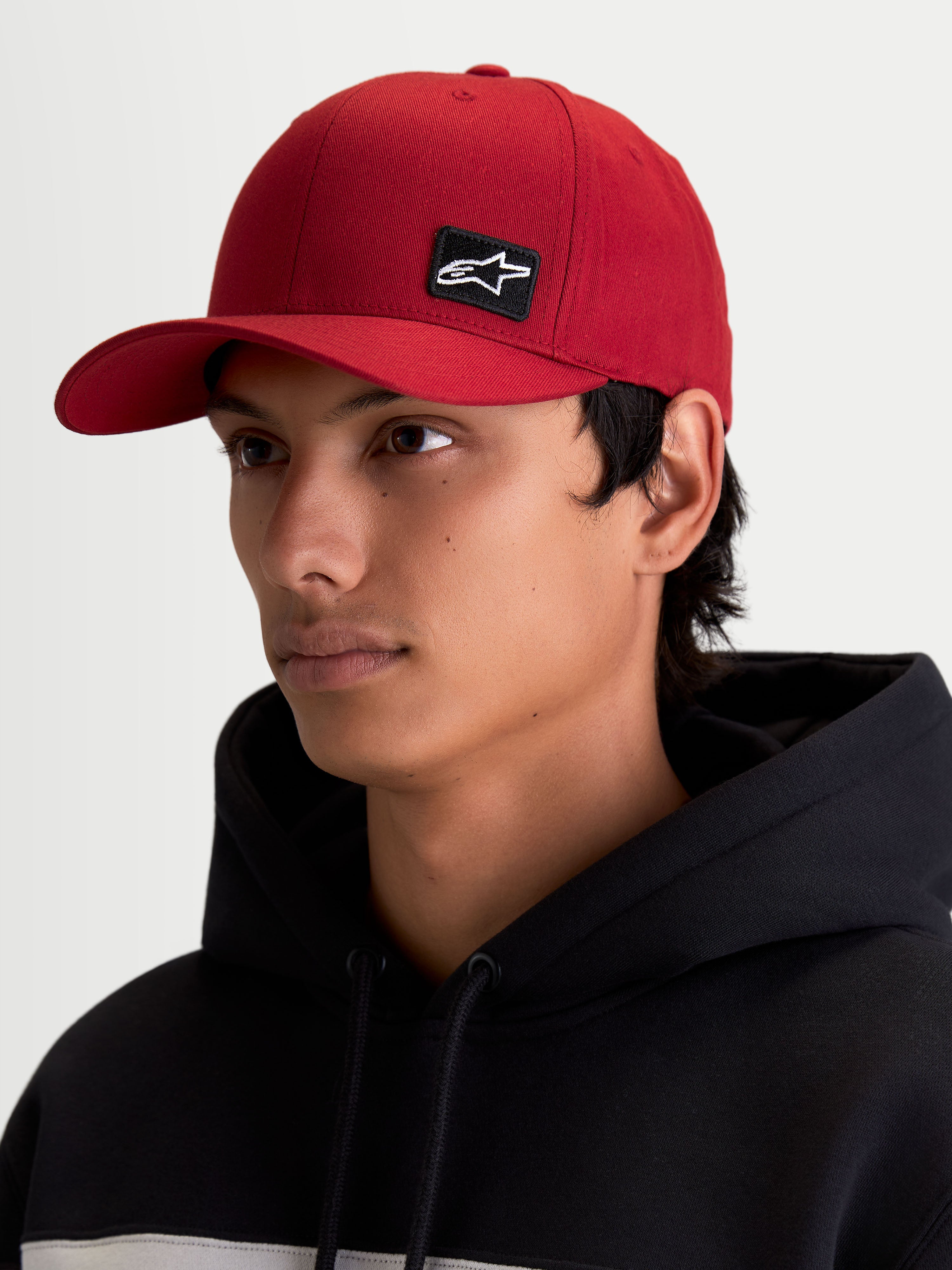 Alpinestars Pivot Hat, Sportswear Lifestyle Cap, Men and Women, Dark Red, featuring a curved bill, structured crown, and a small black Astars embroidered logo patch on the front, shown on-model.