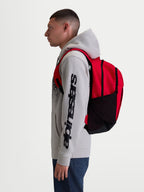 Alpinestars GFX Boss Backpack, Red and Black 20L Sportswear Daypack, durable 600D polyester with side mesh water bottle pockets and padded air mesh shoulder straps, shown on-model for urban commuting and daily use.