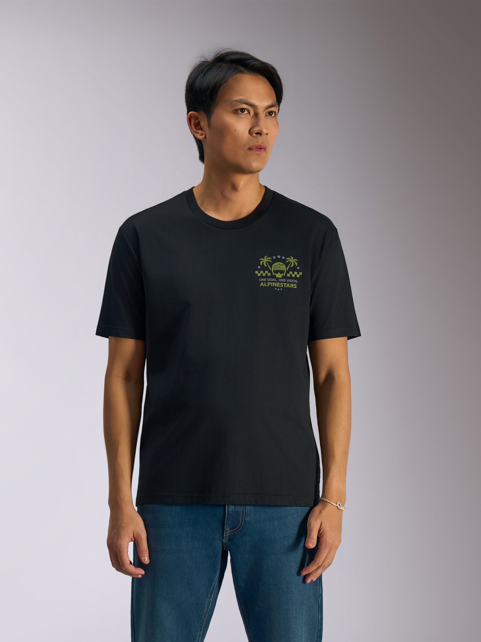 Alpinestars Order CSF Tee, Short Sleeve T-Shirt, Black, Green graphic with helmet and palm trees on the chest, modeled with blue jeans, casual motorsport streetwear