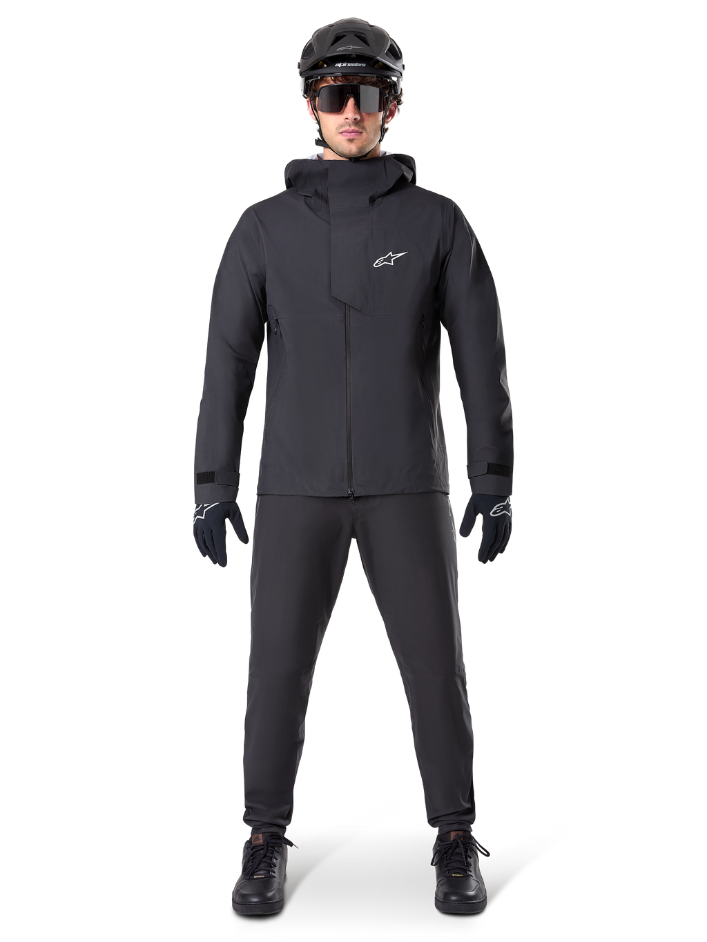 Alpinestars A-Dura Elite Waterproof Jacket, Black, worn with matching cycling pants and gloves, black helmet and sunglasses, featuring a white Astars logo on the chest, high-performance technical design for mountain biking
