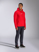 Alpinestars Frontal Hoodie, Red, male model wearing pull-over fleece hoodie with white A-star chest logo, kangaroo pocket, drawstring hood, paired with dark denim jeans, casual motorsport-inspired streetwear