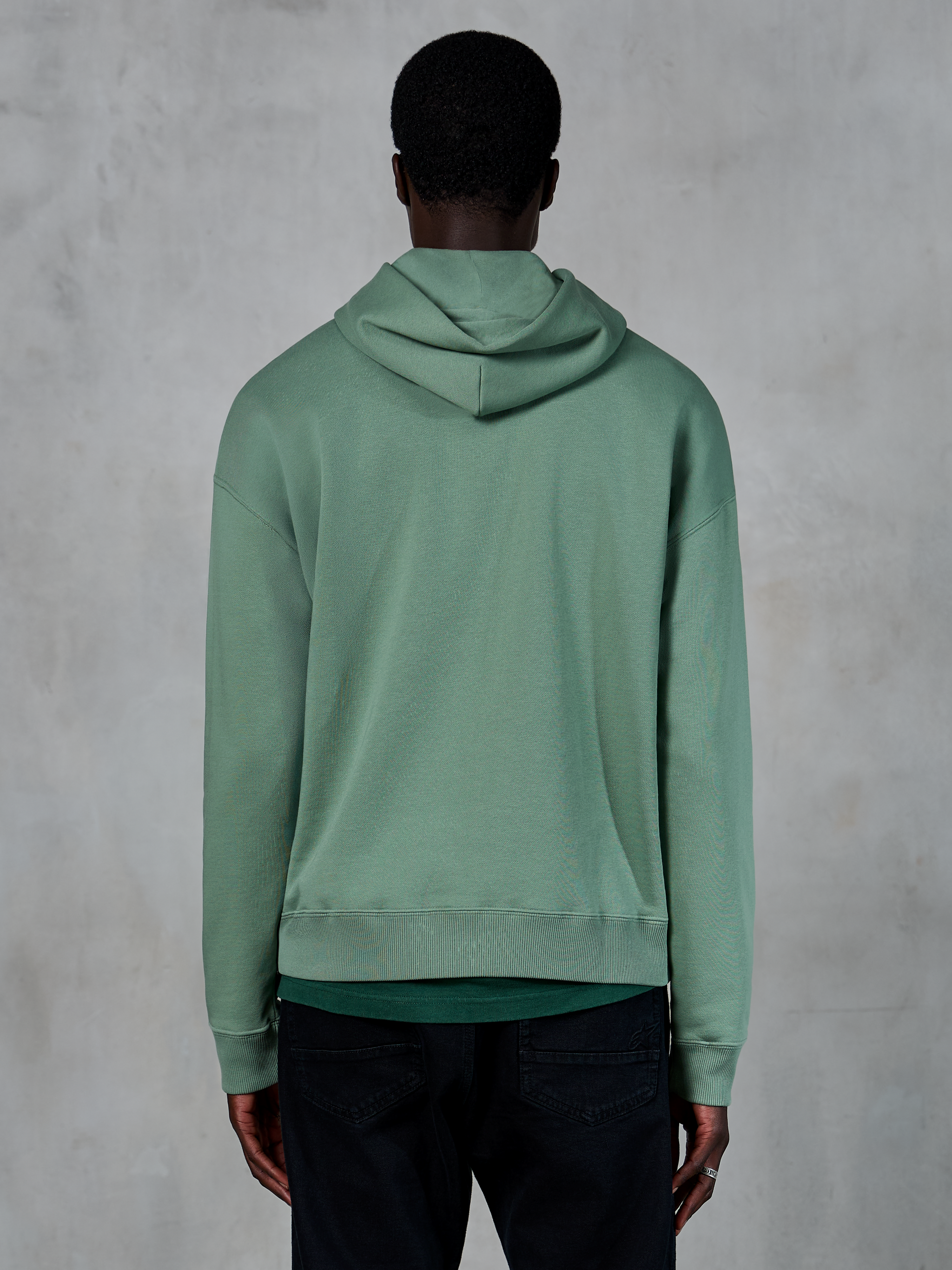 Alpinestars Essentials Ageless Hoodie, casual sportswear, Cactus green, rear view on model, garment stone wash finish, paired with black pants, minimalist lifestyle design