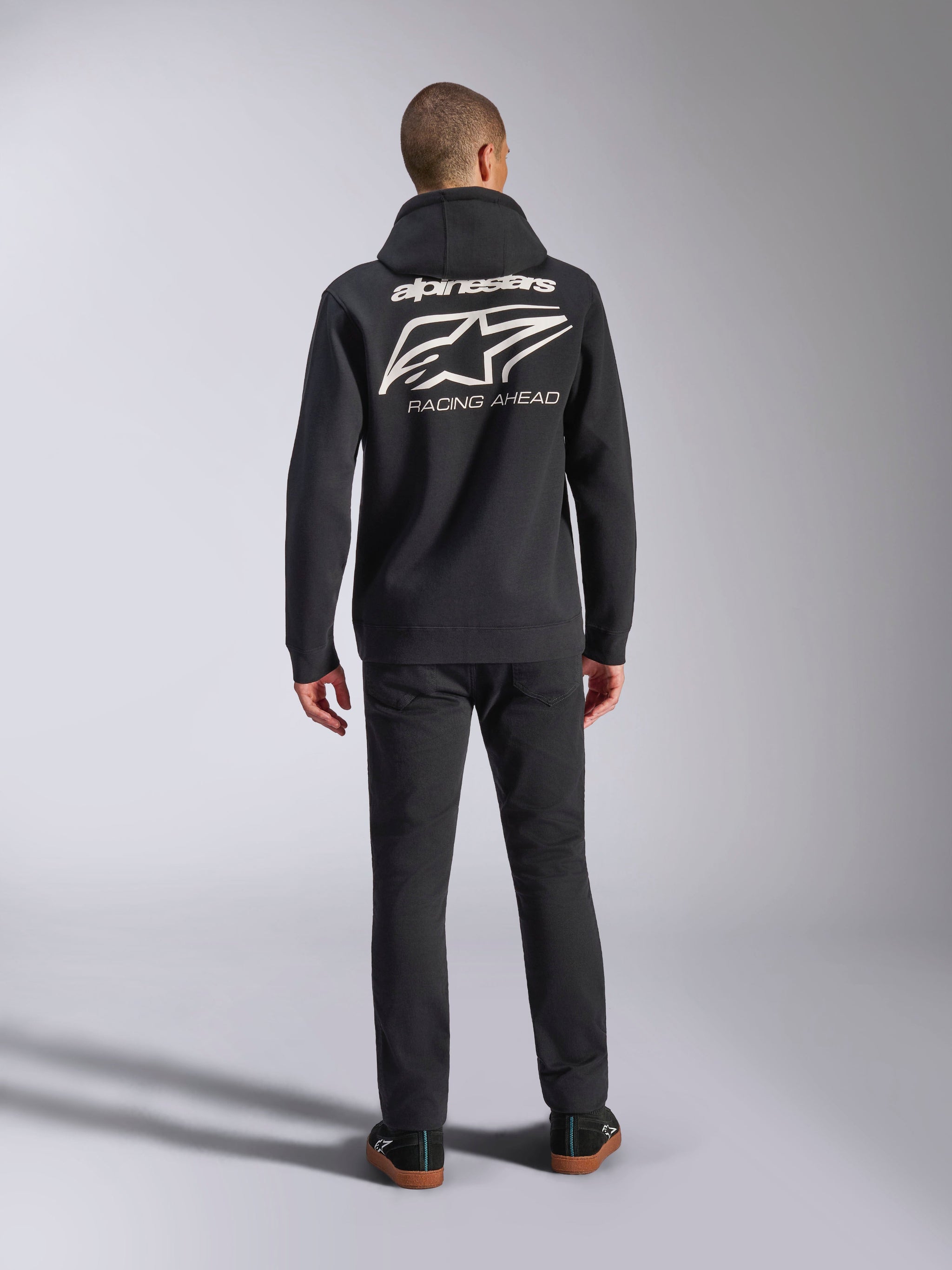 Alpinestars Formulation Hoodie, black, back view on model featuring large white Alpinestars logo and 'Racing Ahead' text, casual motorsport-inspired streetwear