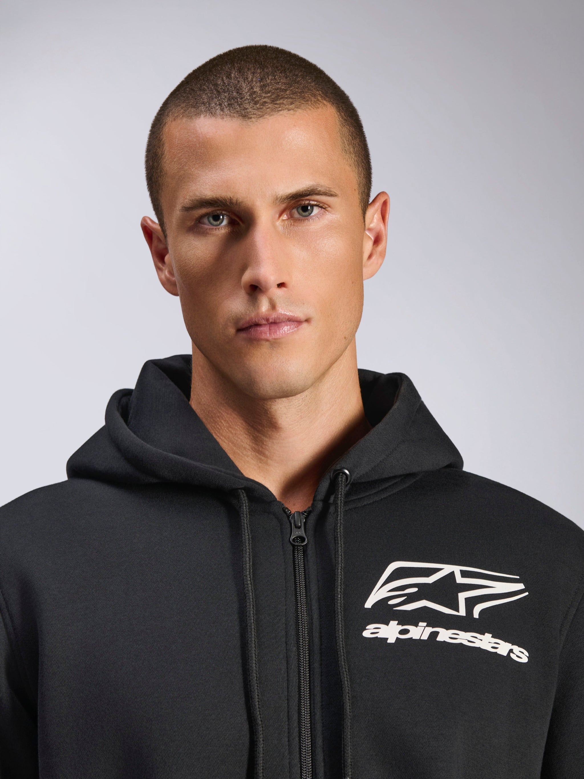 Alpinestars Formulation Hoodie, Black, male model wearing zip-front poly fleece, white Alpinestars logo on chest, drawstring hood, casual motorsport-inspired streetwear