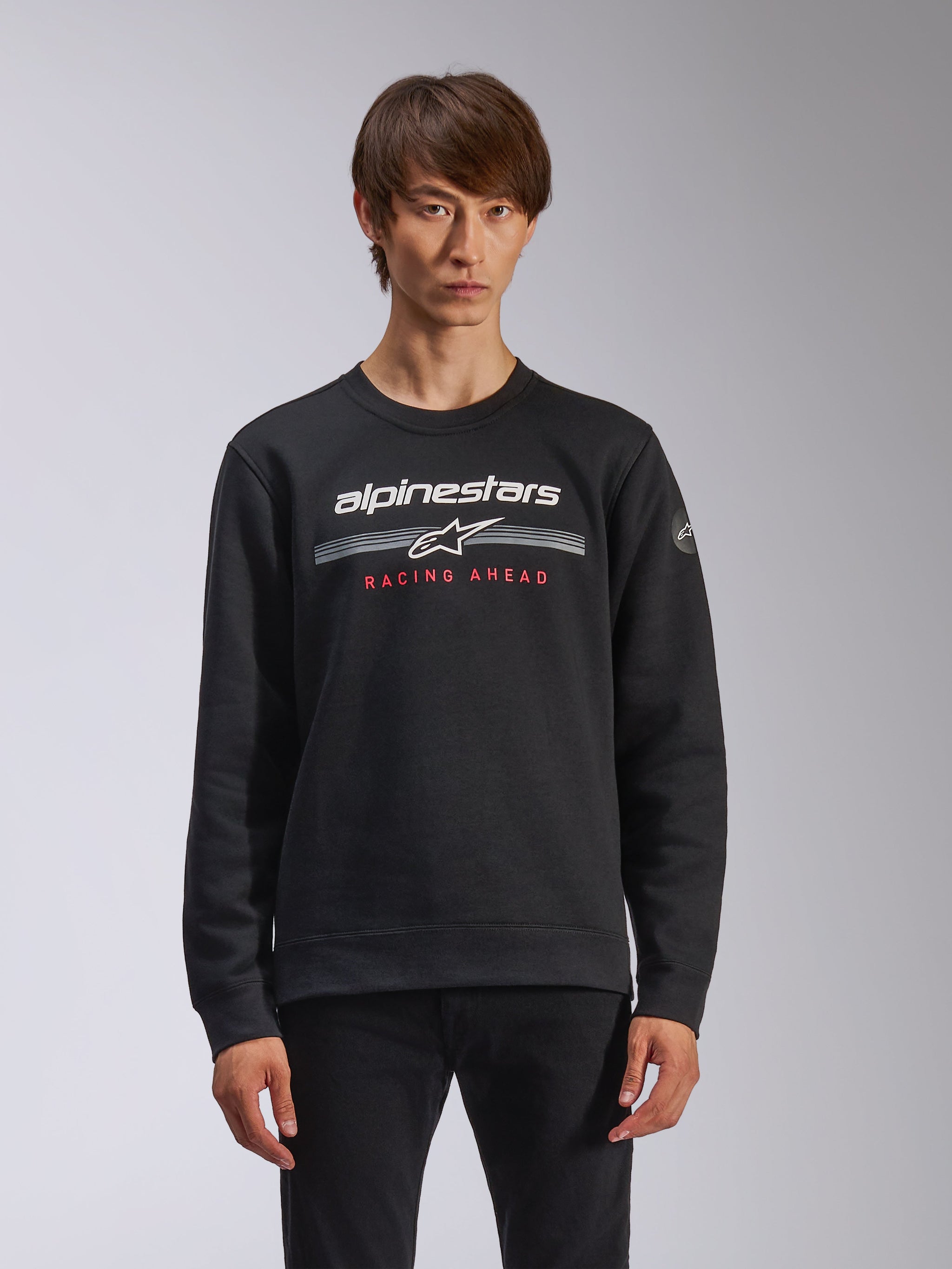 Alpinestars Bettern Crew, Crew Neck Sweatshirt, Black, featuring white Alpinestars branding with horizontal grey stripes and red 'RACING AHEAD' text, casual motorsport streetwear