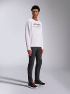 Alpinestars Bettern Crew, White Pullover Sweatshirt, featuring black Alpinestars logo and 'Racing Ahead' red text, casual motorsport streetwear, worn by a model with dark pants and black sneakers