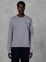 Alpinestars Essentials Ageless Crew, Silver crewneck sweatshirt worn by a model, featuring a small black star logo on the chest, relaxed fit with ribbed cuffs and hem, casual motorsport streetwear