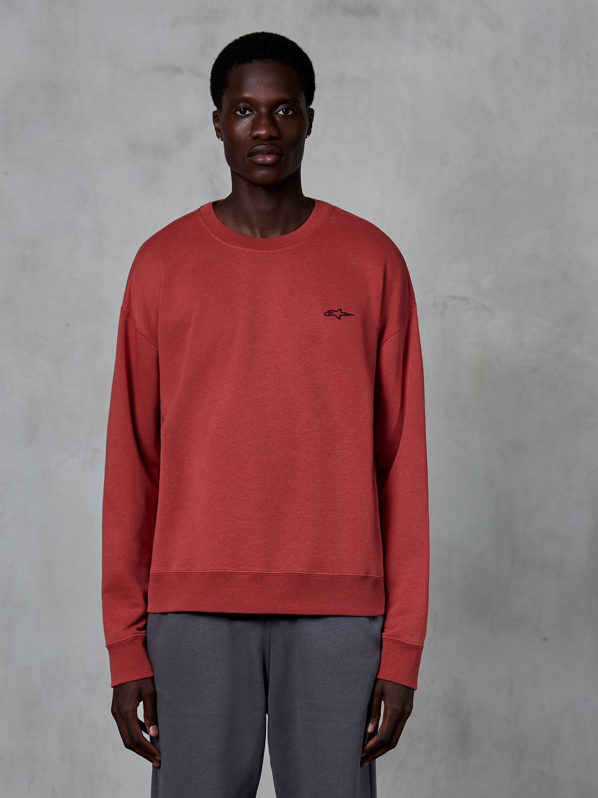 Alpinestars Essentials Ageless Crew, Crewneck Sweatshirt, Brick Red, small black logo on chest, worn by a model with grey pants, premium soft fleece casual streetwear