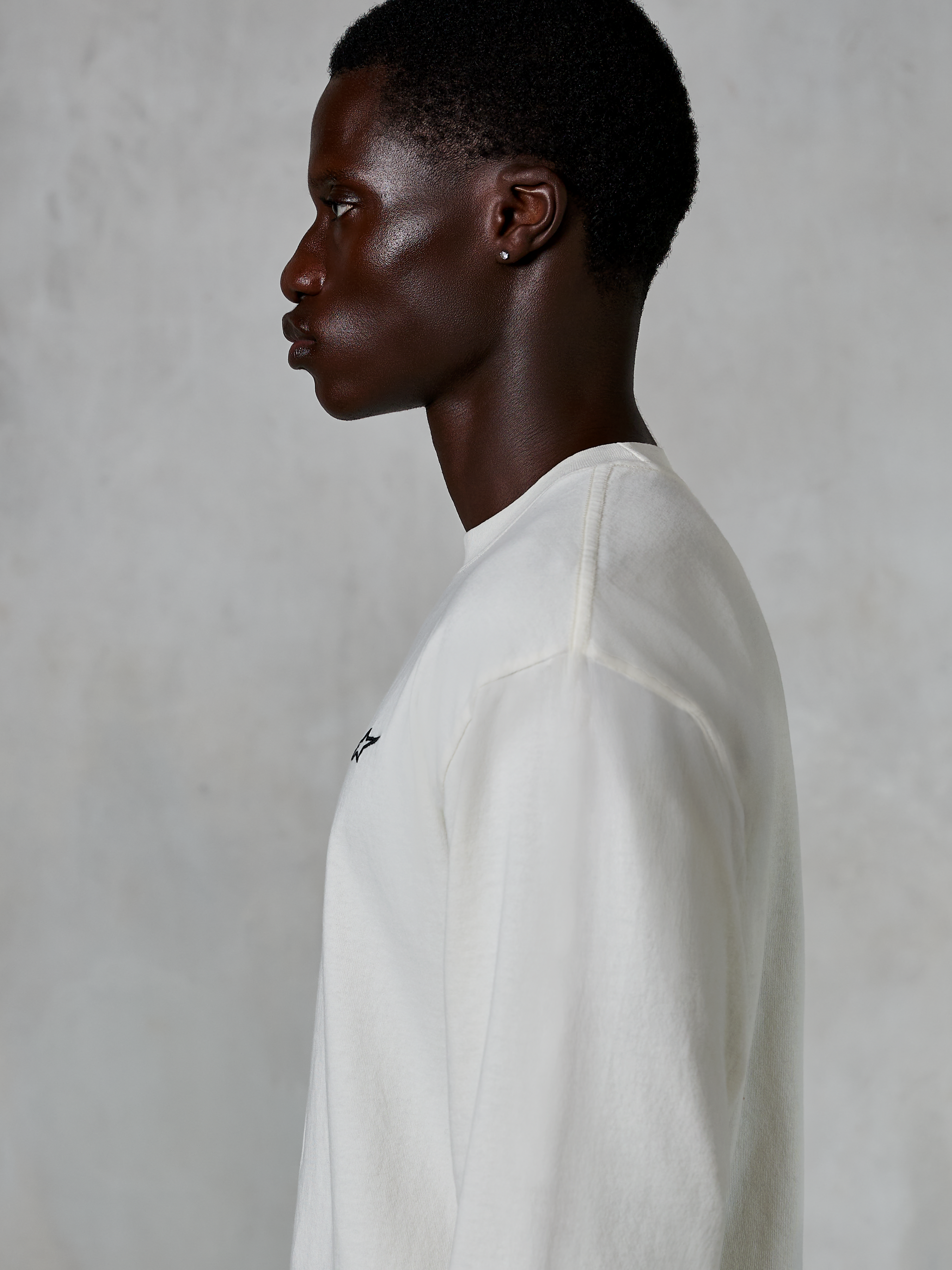 Alpinestars Essentials Ageless LS Tee, Long Sleeve T-Shirt, Off White, profile view of a man wearing the relaxed-fit tee, featuring a small black logo on the chest, casual motorsport-inspired lifestyle apparel