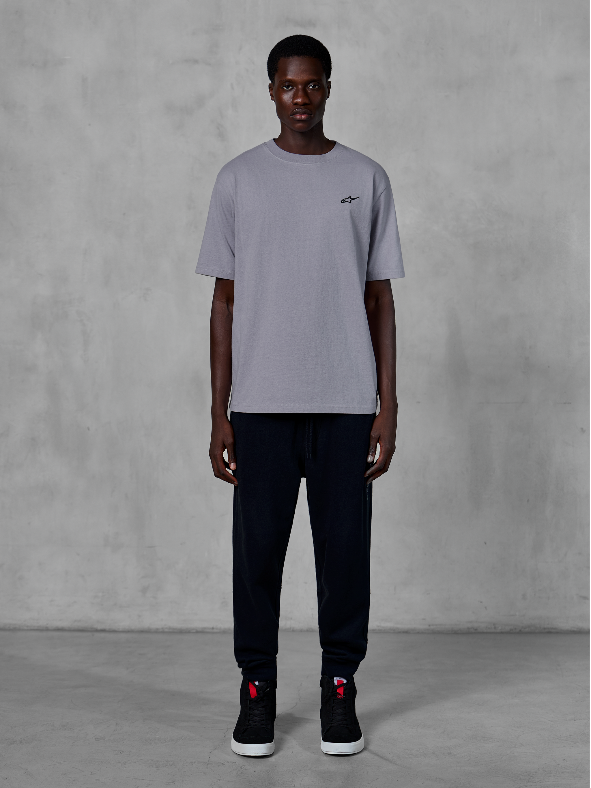 Alpinestars Essentials Ageless SS Tee, Short Sleeve T-Shirt, Silver, featuring a small black logo on the chest, styled with black joggers and sneakers, casual motorsport streetwear