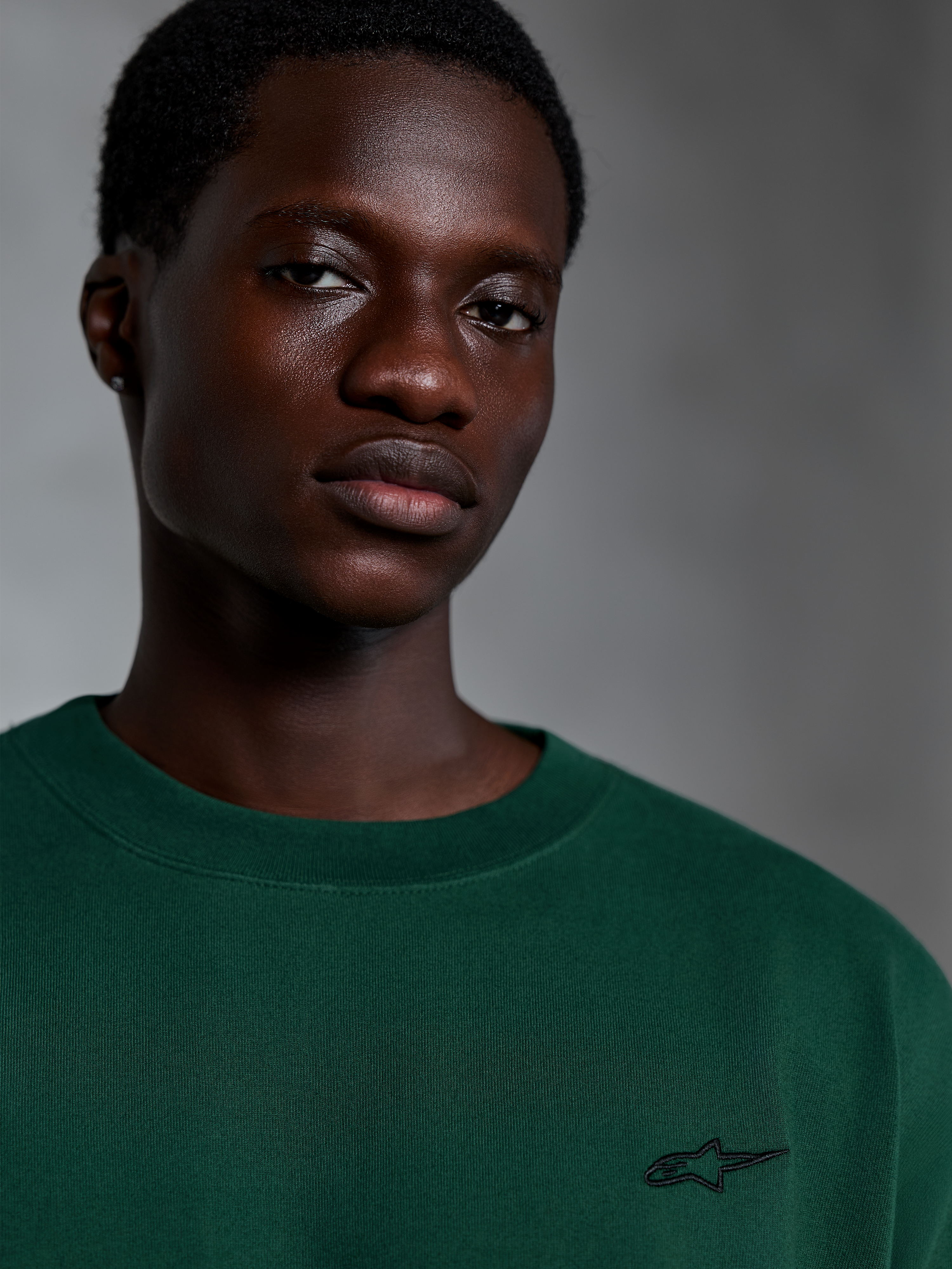 Alpinestars Essentials Ageless SS Tee, Pine Green Short Sleeve T-Shirt, Close-up of model wearing green organic cotton tee with small embroidered logo, casual streetwear design